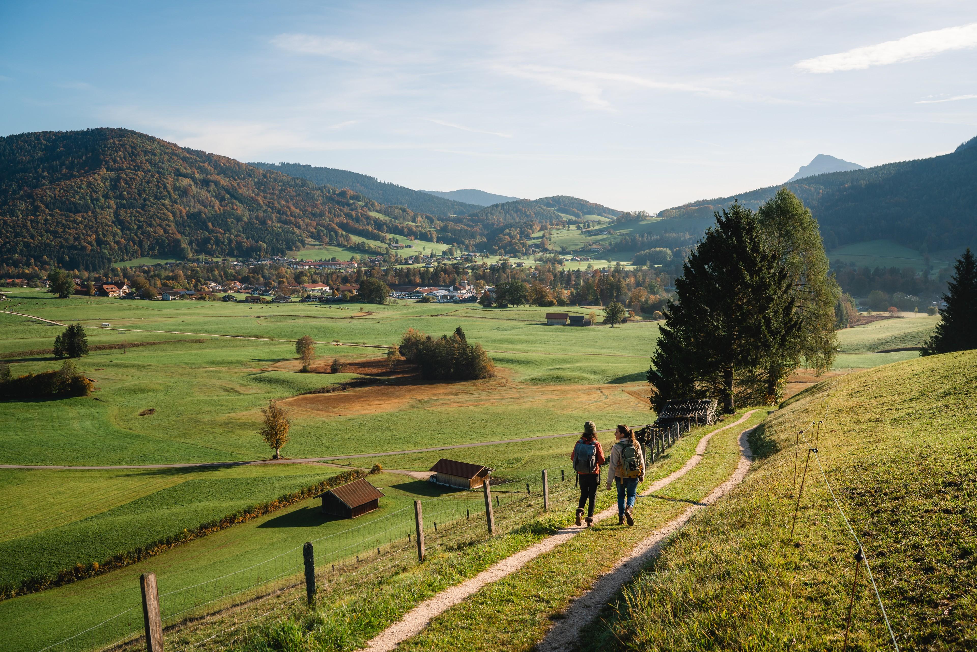 Zwei Personen wandern auf einem Feldweg im Ruhpoldinger Tal