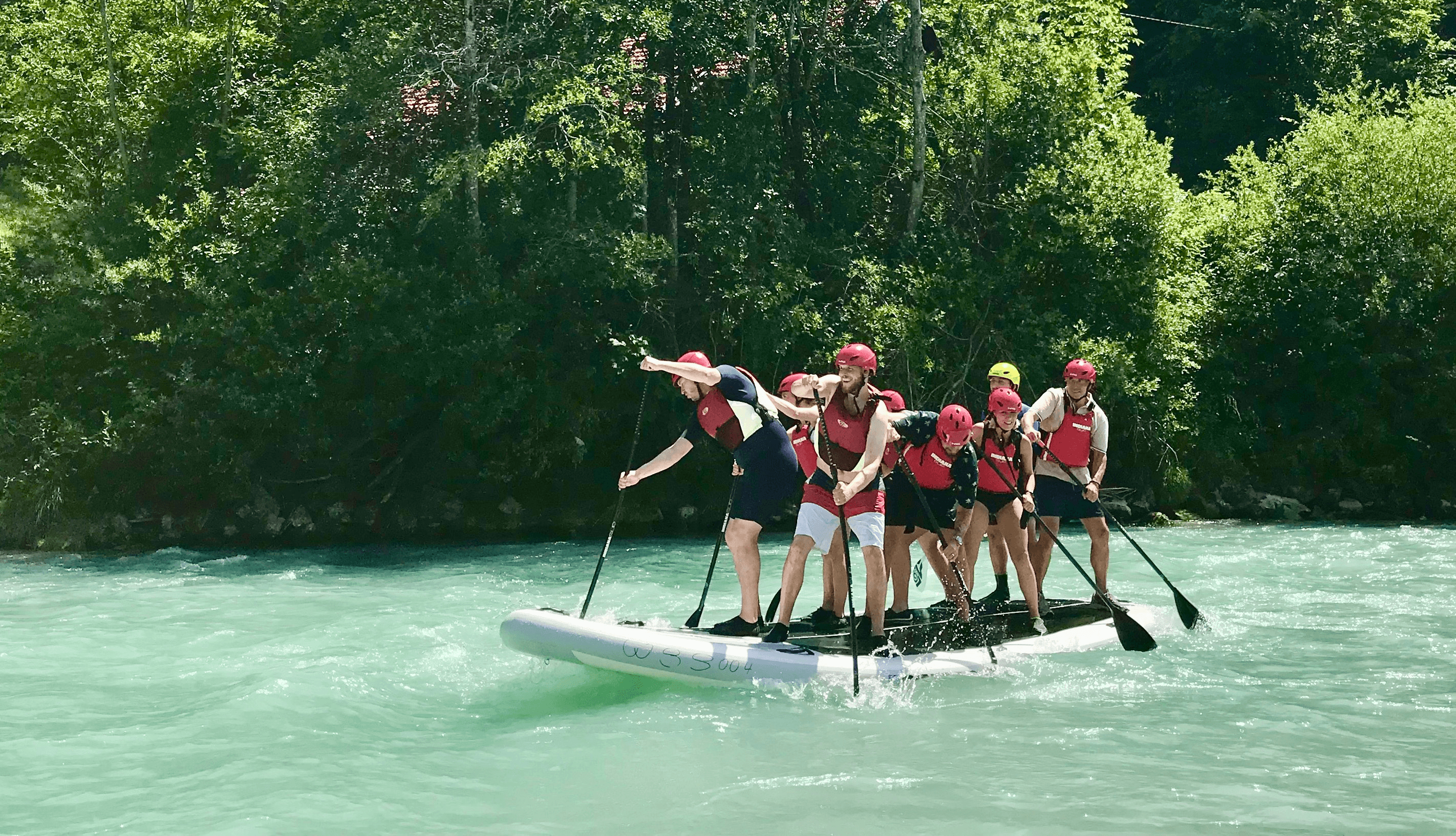 Eine Gruppe steht auf einem Maxi-SUP-Board und paddelt auf einem Gebirgsfluss