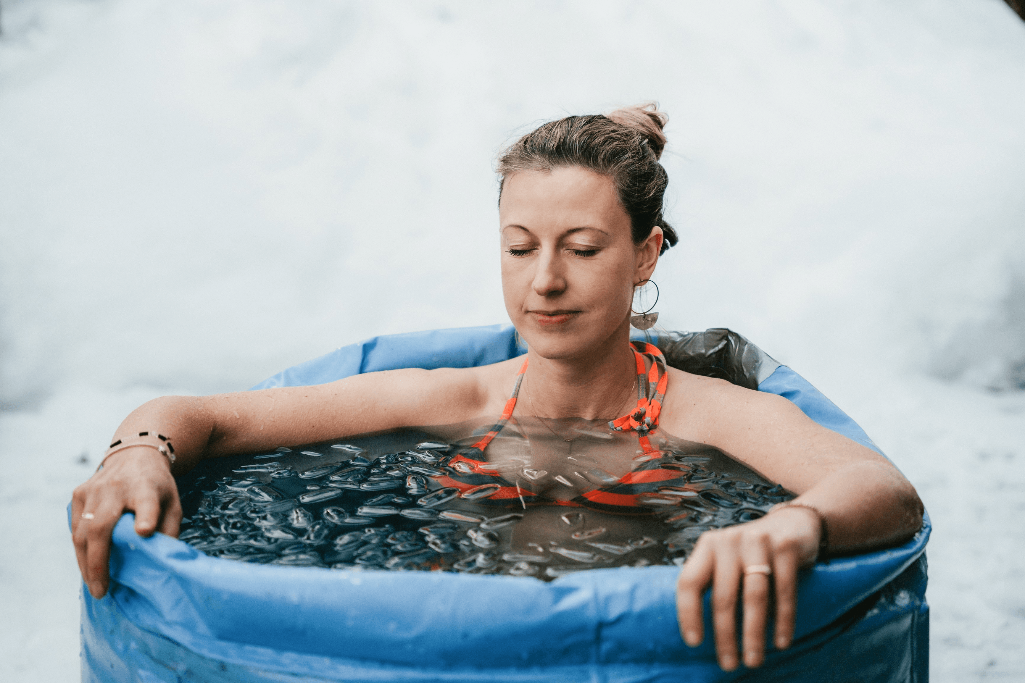 Martina Weifenbach sitzt mit geschlossenen Augen in einer aufblasbaren Eisbaden-Tonne, die mit Eis gefüllt ist