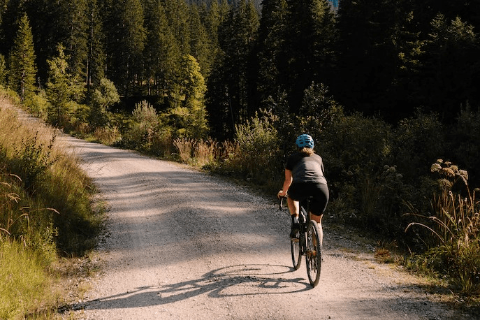 Ein Person fährt auf einer unbefestigten Straße in den Bergen Fahrrad