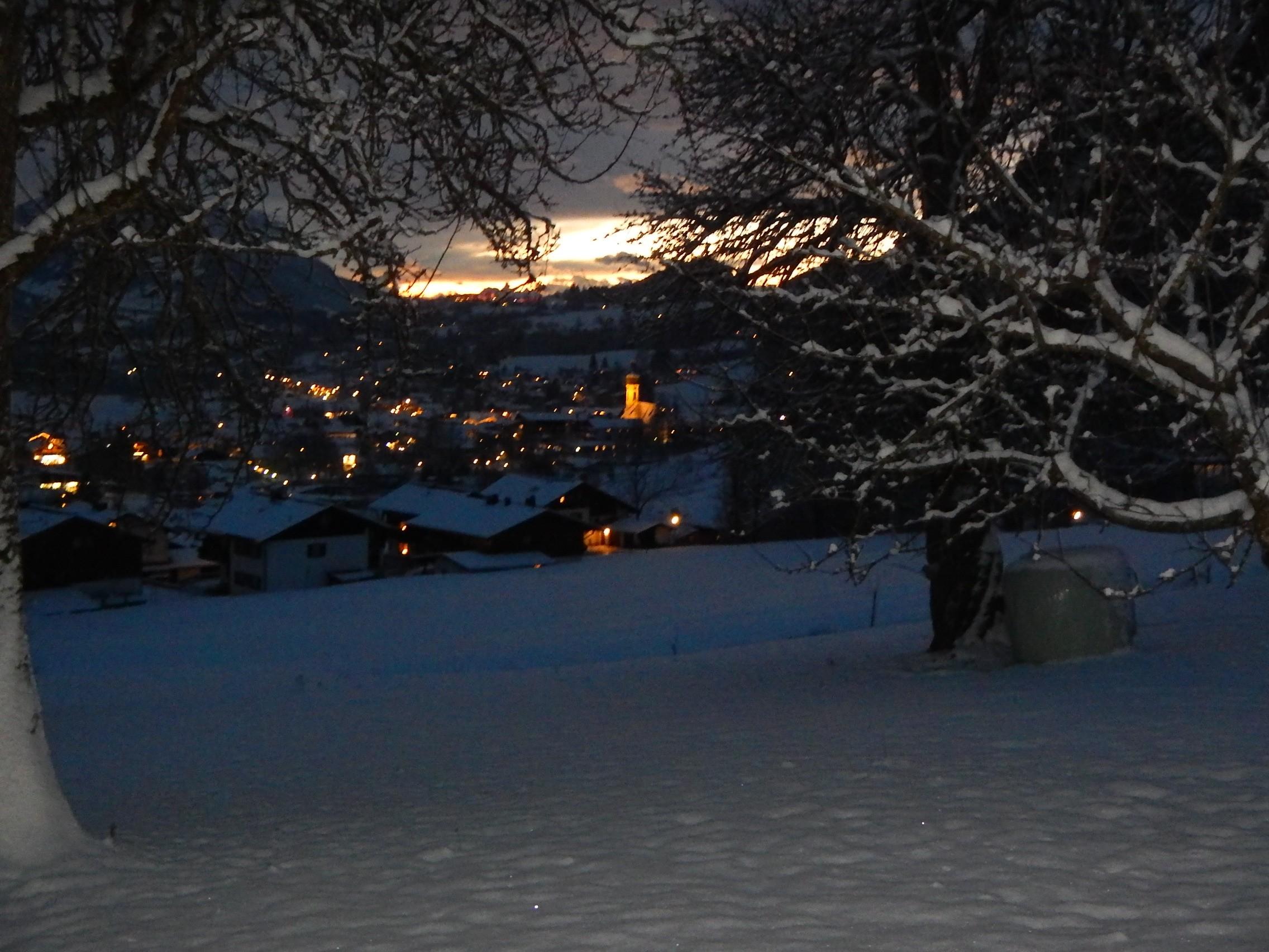 Beleuchtete Häuser im verschneiten Reit im Winkl am Abend