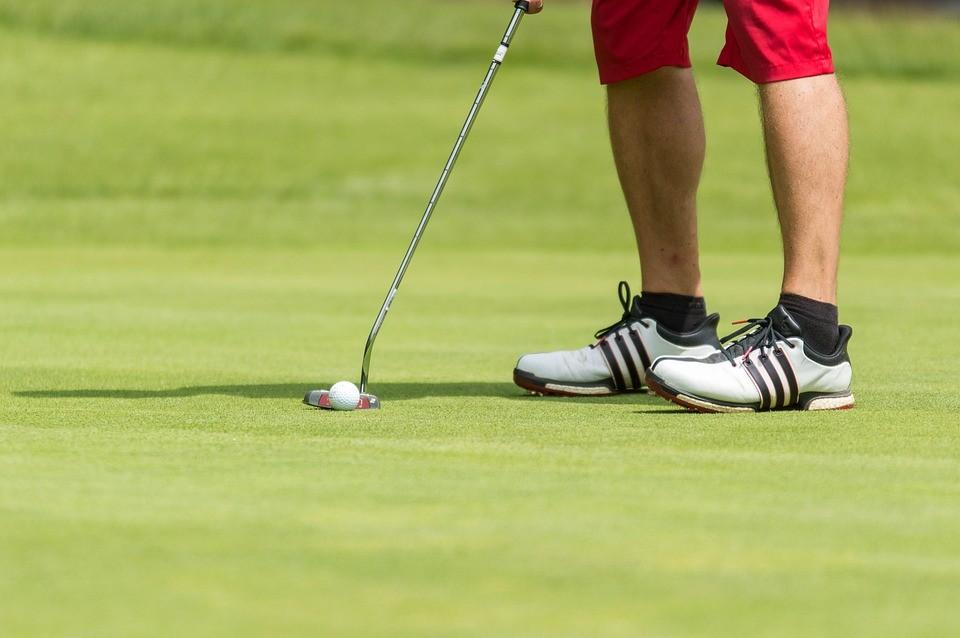 Ein Golfer auf dem Putting Green mit Schläger und Ball