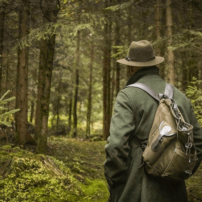 Eine grün gekleidete Person steht während einer Vogelwanderung im Wald und blickt auf Bäume