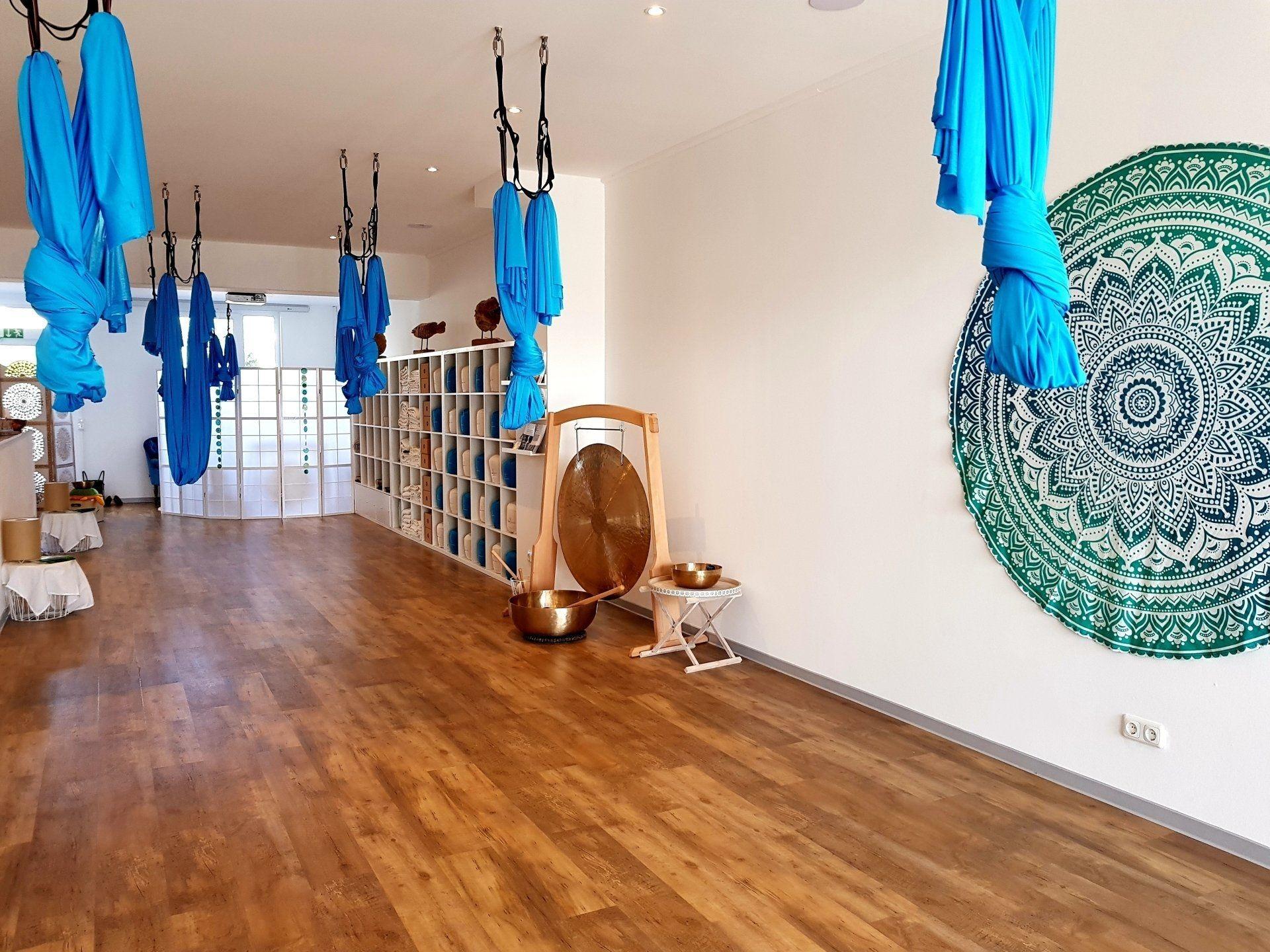 In einem Raum hängen blaue Aerial-Yoga-Tücher von der Decke