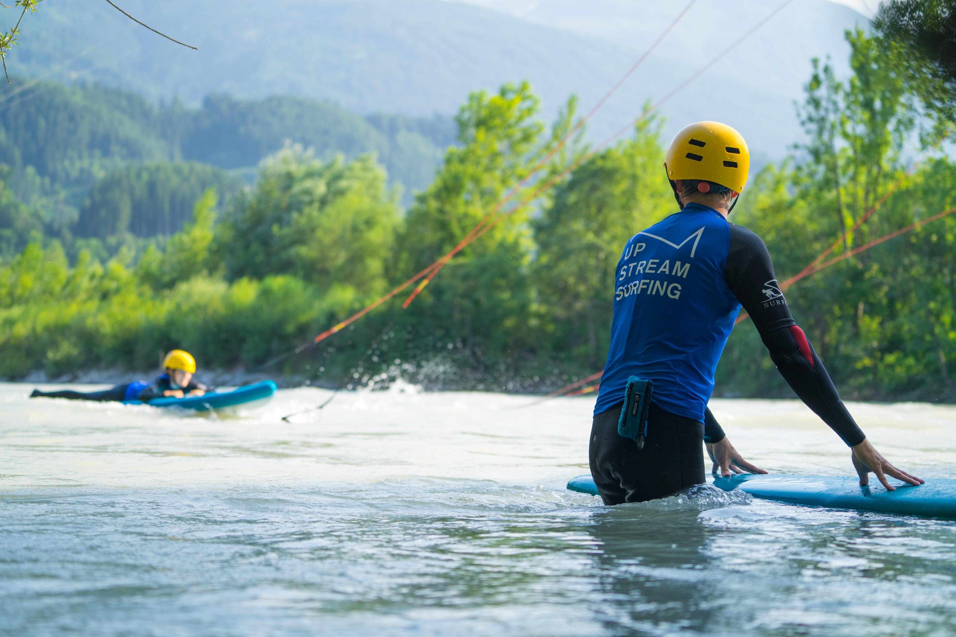 Eine Frau liegt auf einem Surfbrett auf dem Inn