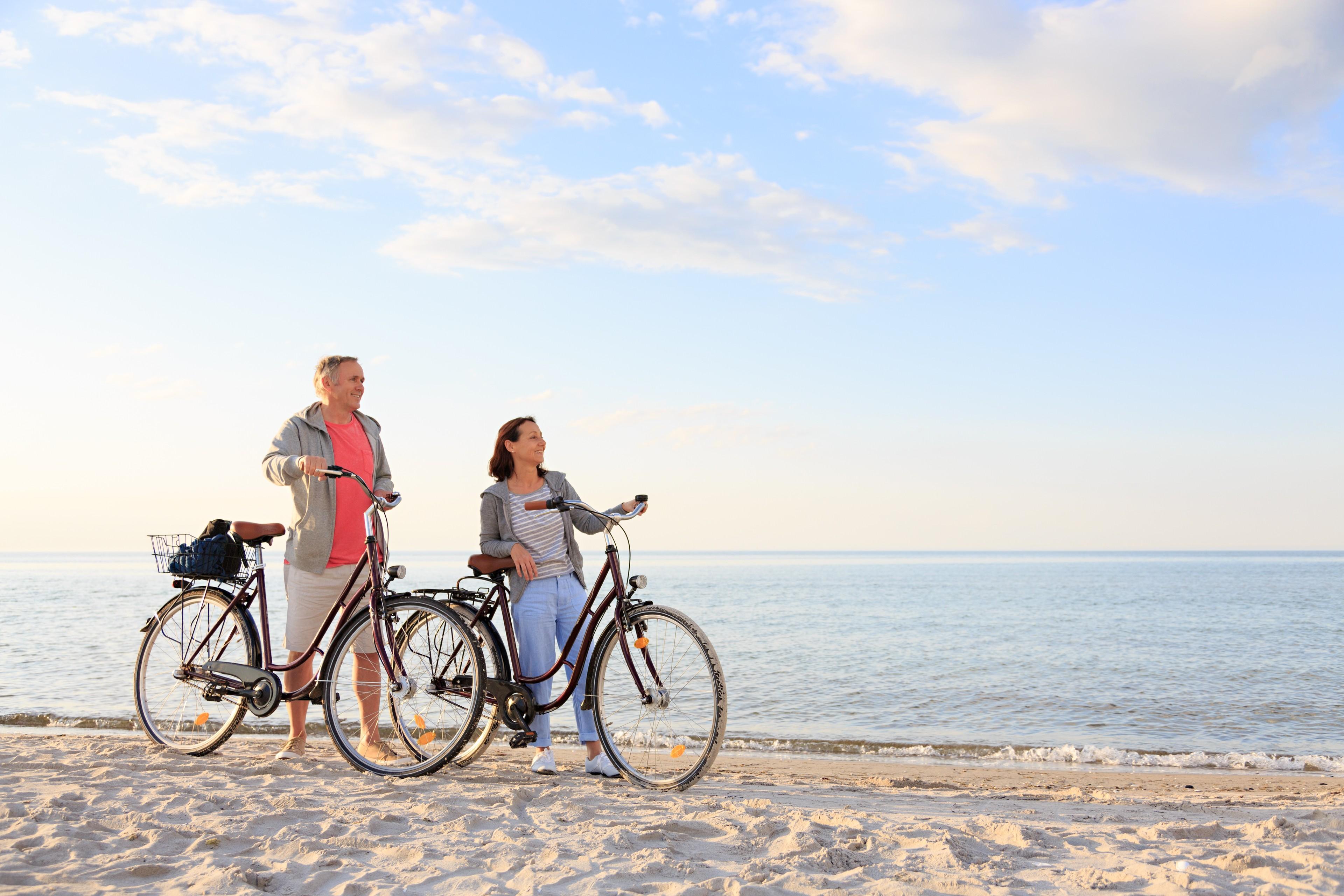 Ein Mann und eine Frau stehen neben ihren Fahrrädern am Strand