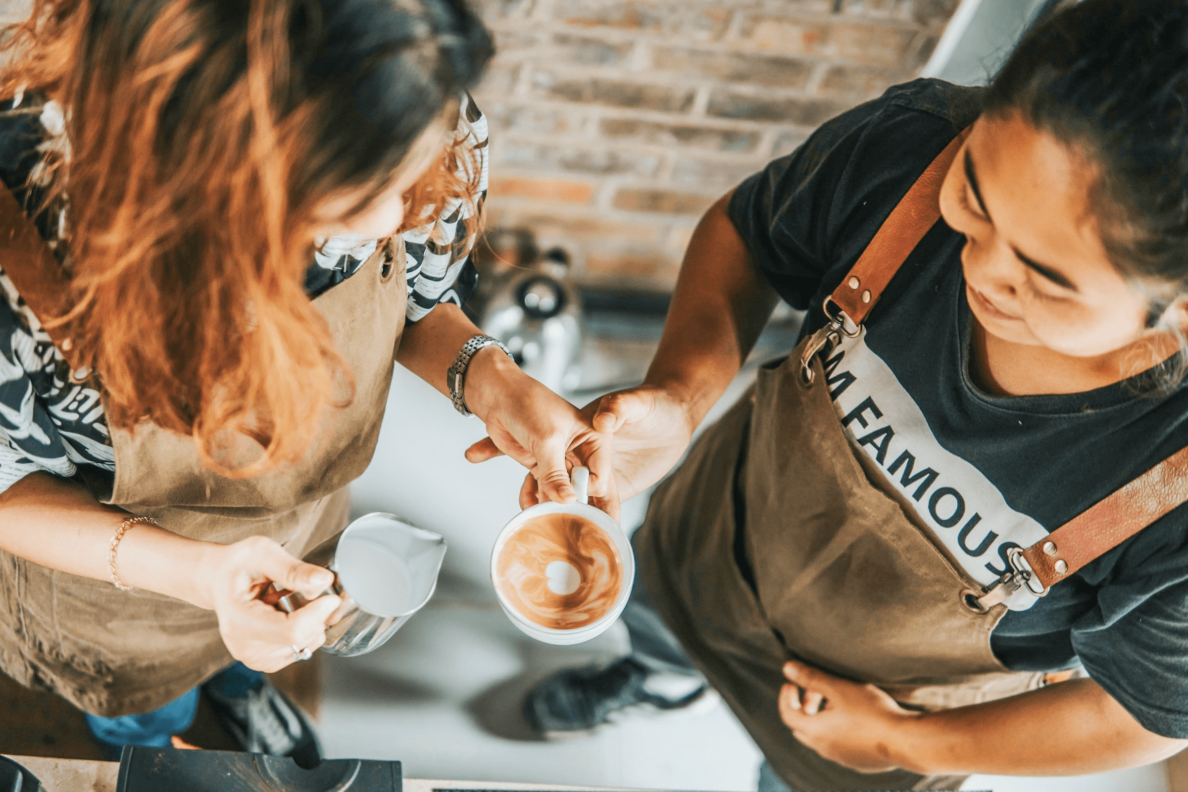 Zwei Personen gießen geschäumte Milch bei einem Barista-Workshop