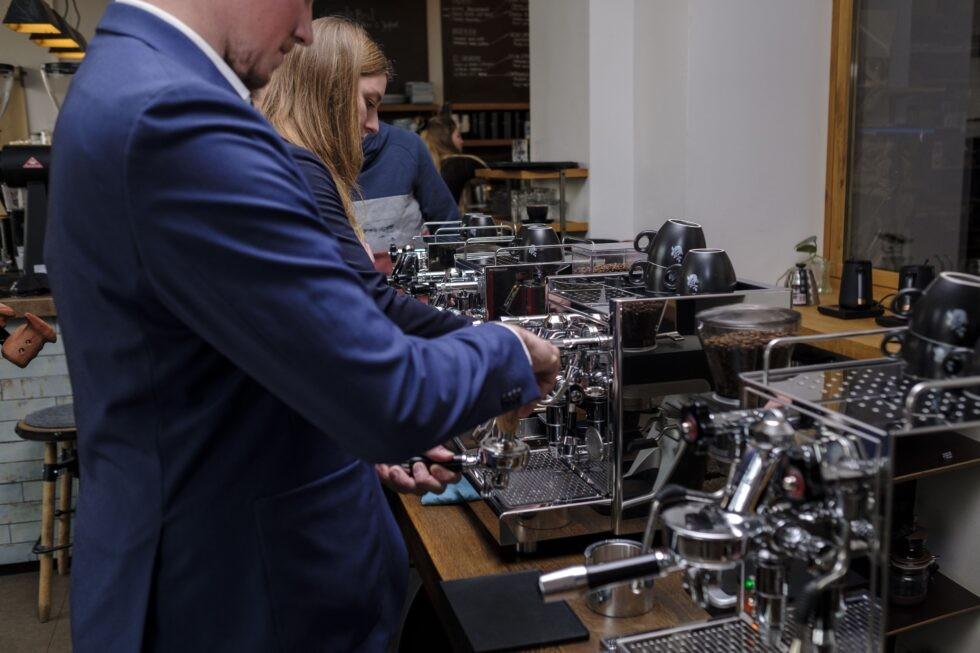 Personen bereiten bei einem Barista-Workshop Espresso an einer Siebträgermaschine zu