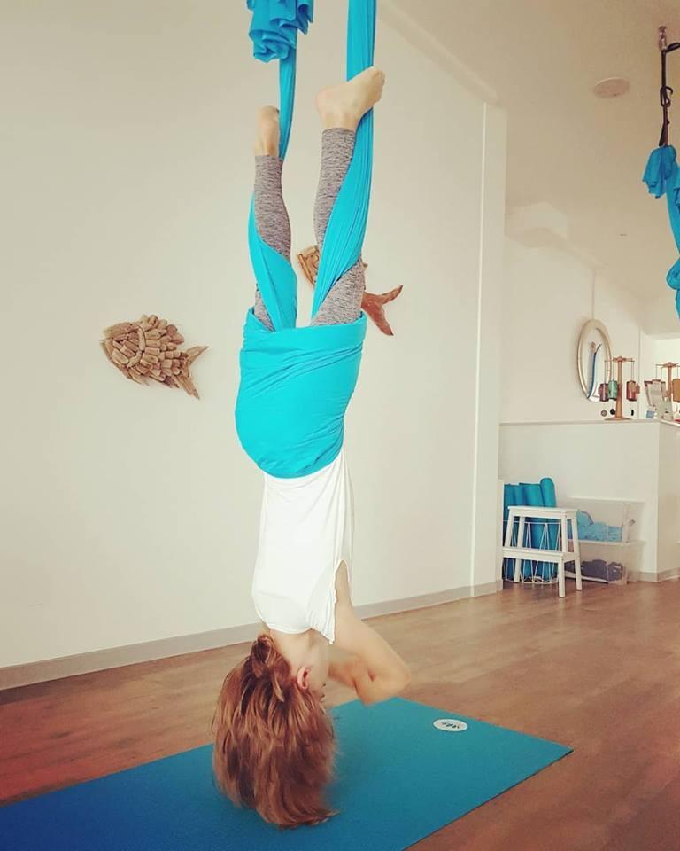 Ein Kind hängt kopfüber in einem Aerial-Yoga-Tuch