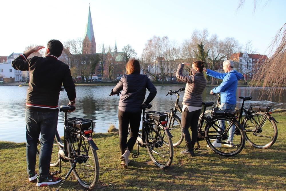Vier Personen stehen mit E-Bikes an einem See in Lübeck