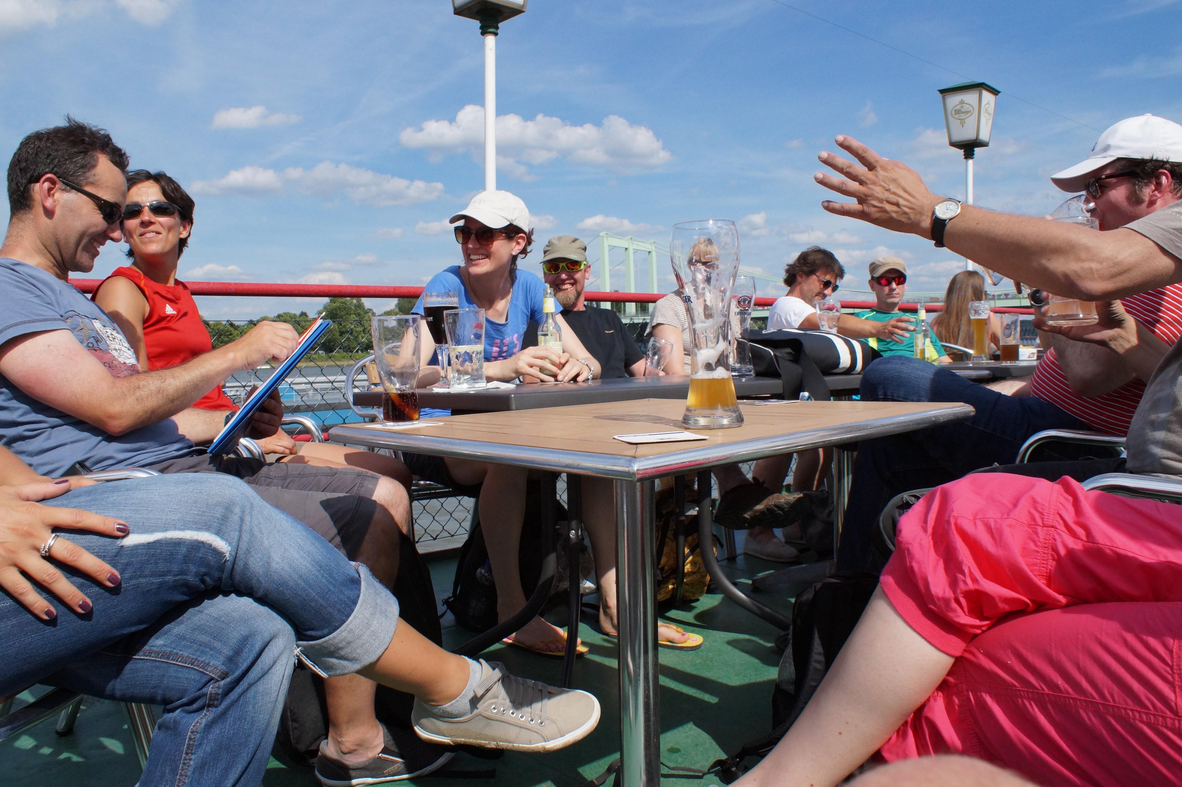 Teilnehmende einer Rafting-Tour sitzen nach der Tour an einem Tisch mit Getränken