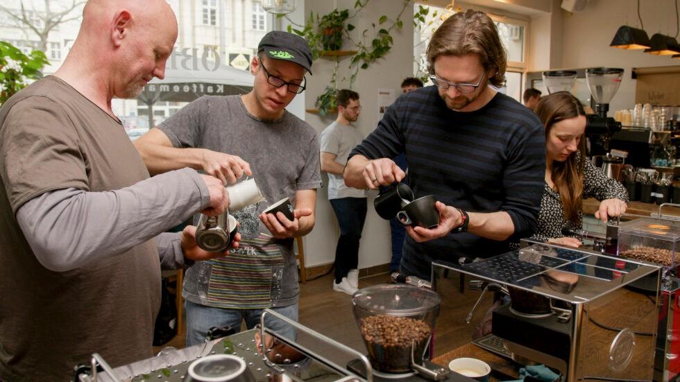 Eine Gruppe gießt Milch beim Latte-Art-Kurs in Leipzig