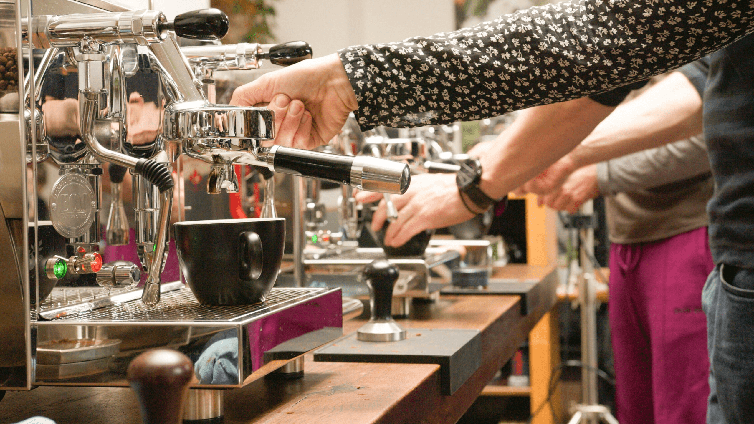 Personen üben bei einem Barista-Workshop an Siebträgermaschinen