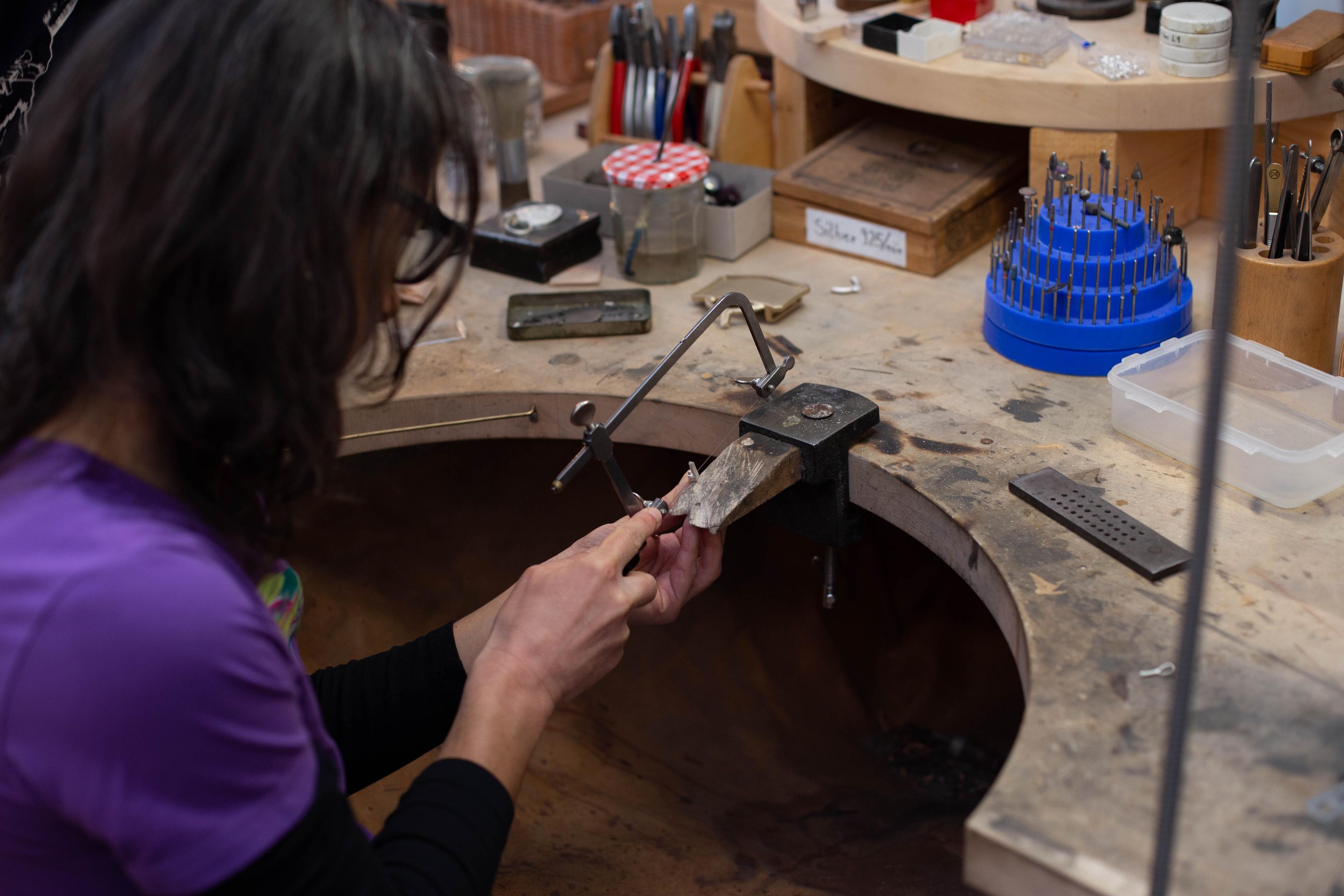 Eine Teilnehmerin stellt bei einem Schmuckworkshop ein Mini-Gipfelkreuz her