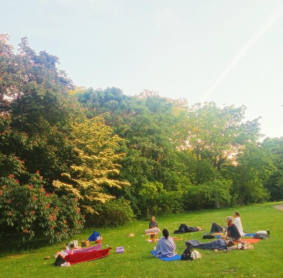 Menschen liegen und sitzen bei einer Achtsamkeitsmeditation auf einer Wiese