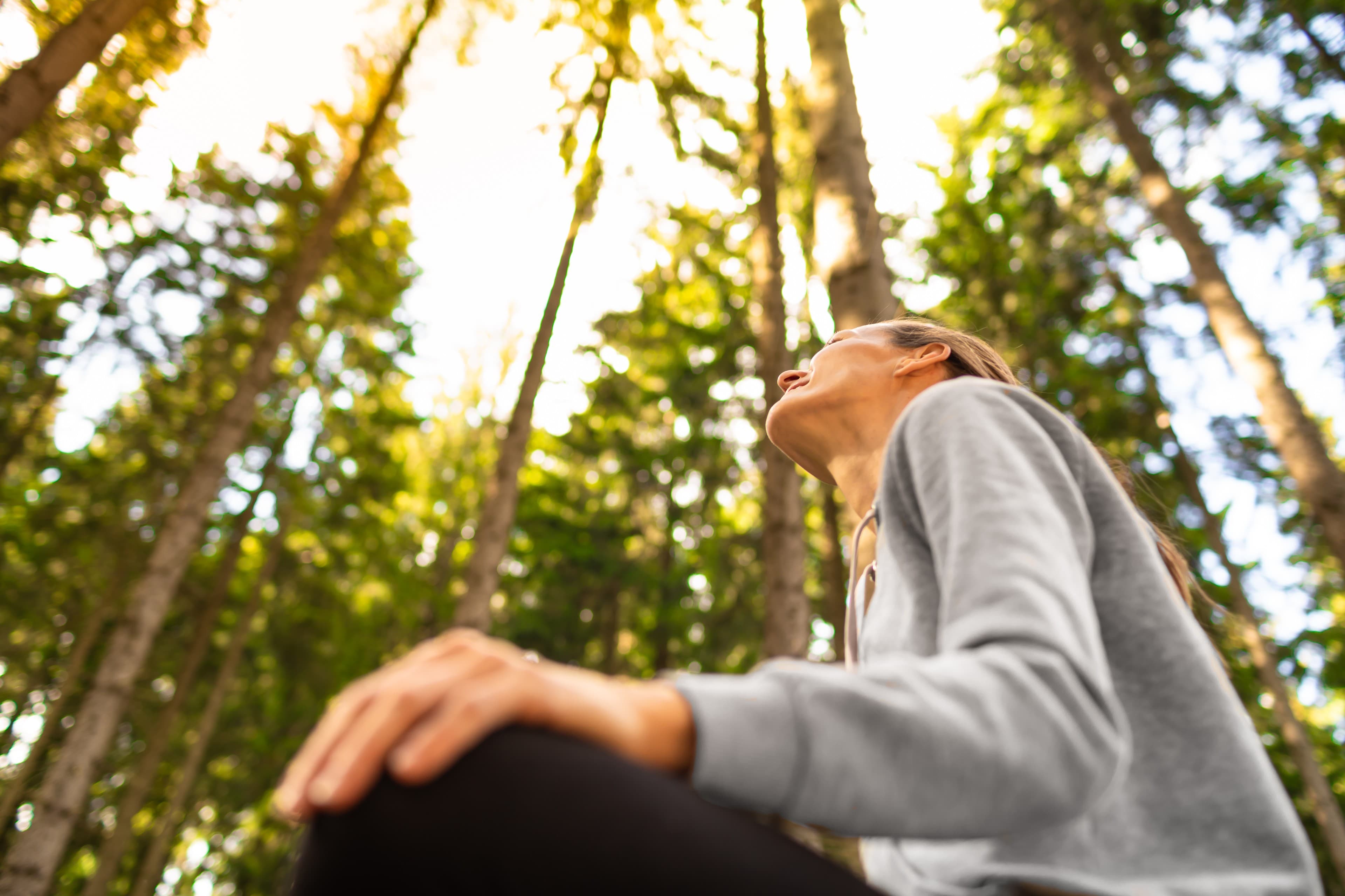 Eine Frau meditiert beim indigenen Heilyoga im Wald