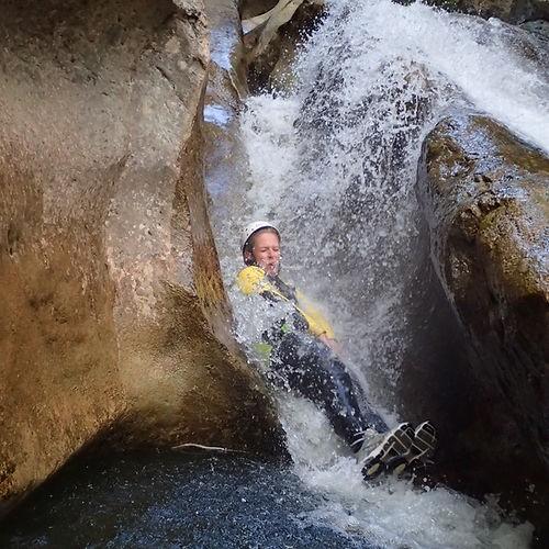 Eine Person rutscht beim Canyoning in der Starzlachklamm eine natürliche Wasserrutsche hinab
