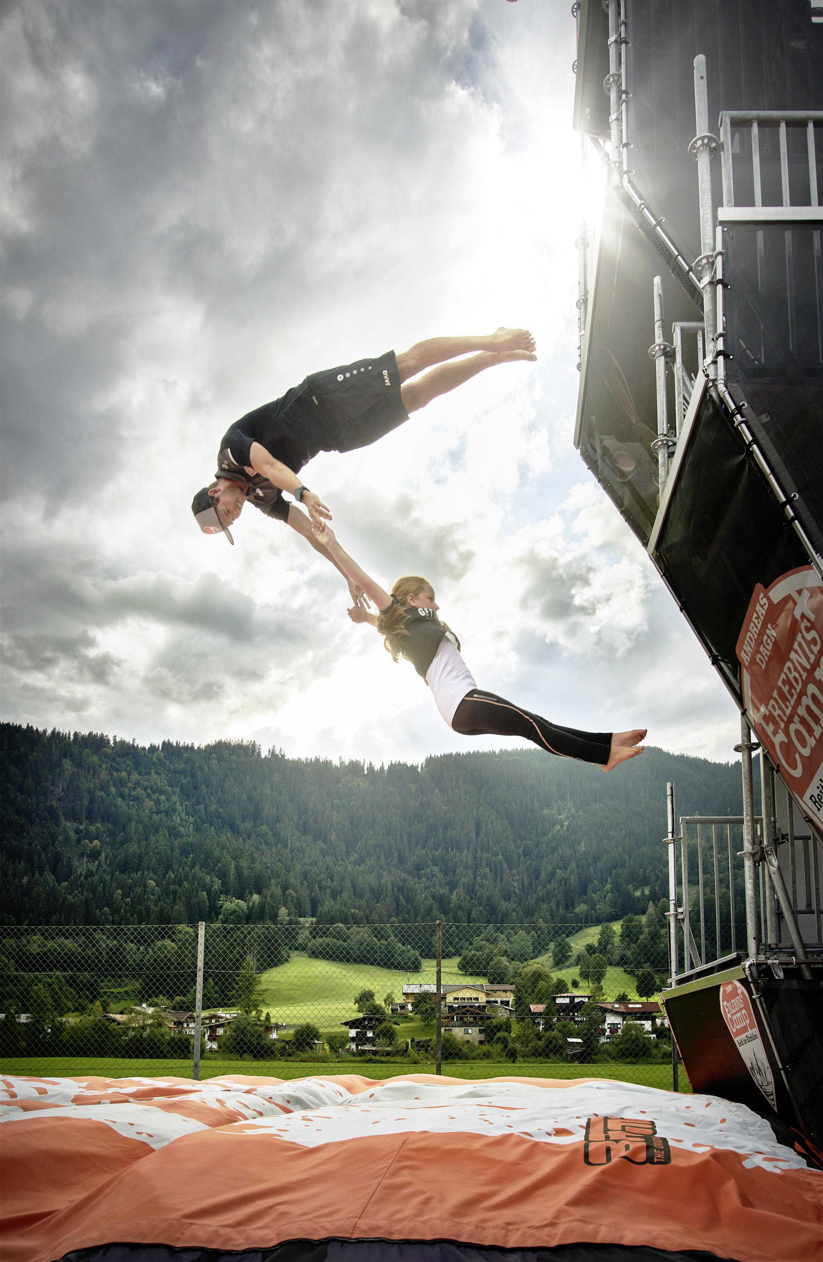 2 Personen springen beim Kinder-Programm bei Kitzbühel in eine gepolsterte Matte