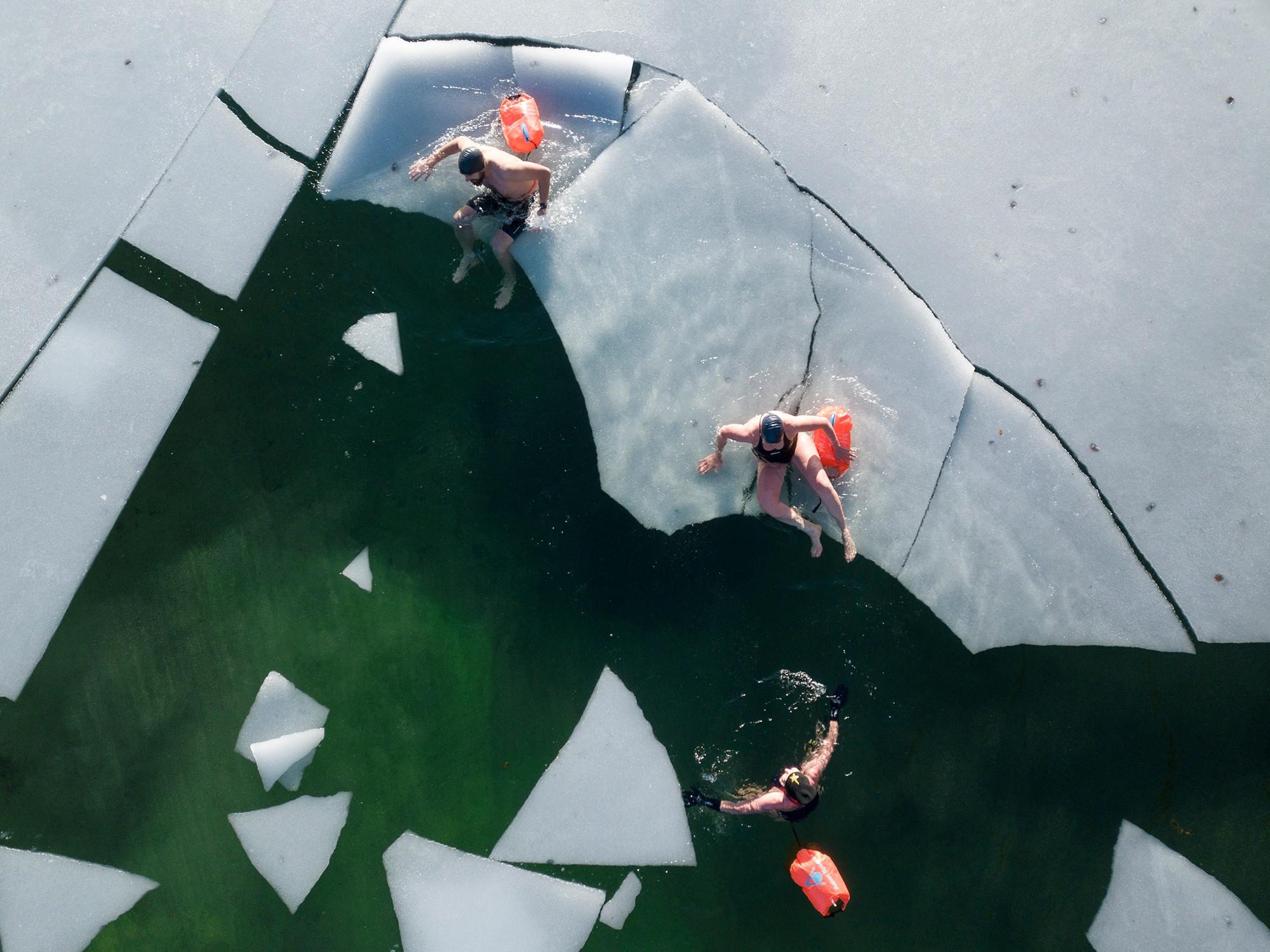 Menschen im Wasser und auf Eisschollen beim Eisbaden in Ruhpolding