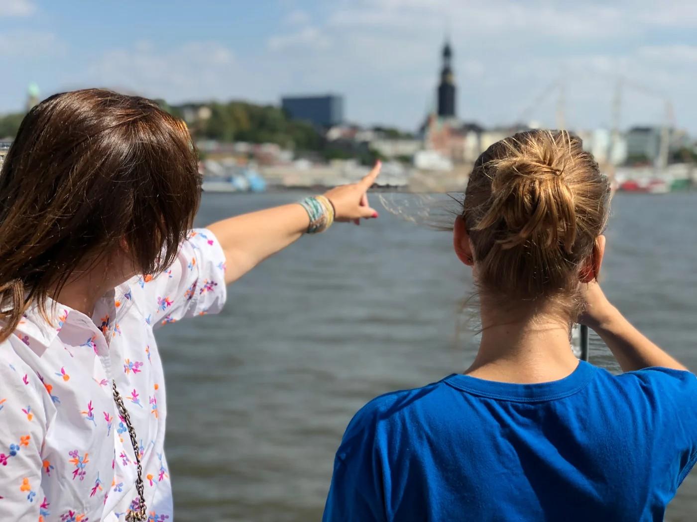 Eine Person zeigt einer anderen eine Sehenswürdigkeit bei einer Fahrrad-Sightseeing-Tour durch Hamburg