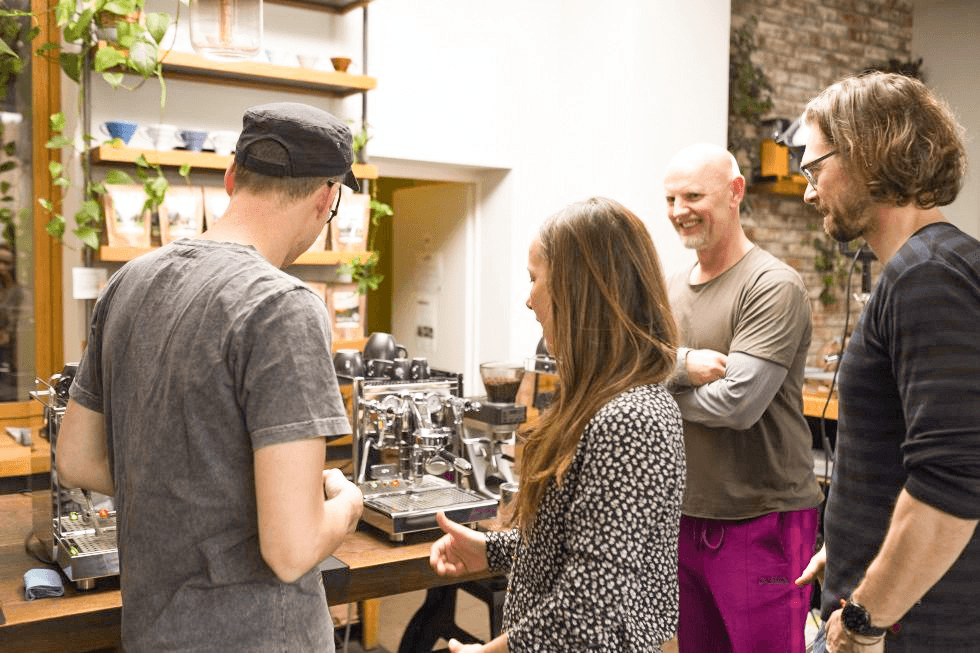 Personen stehen bei einem Barista-Kurs um eine Siebträgermaschine