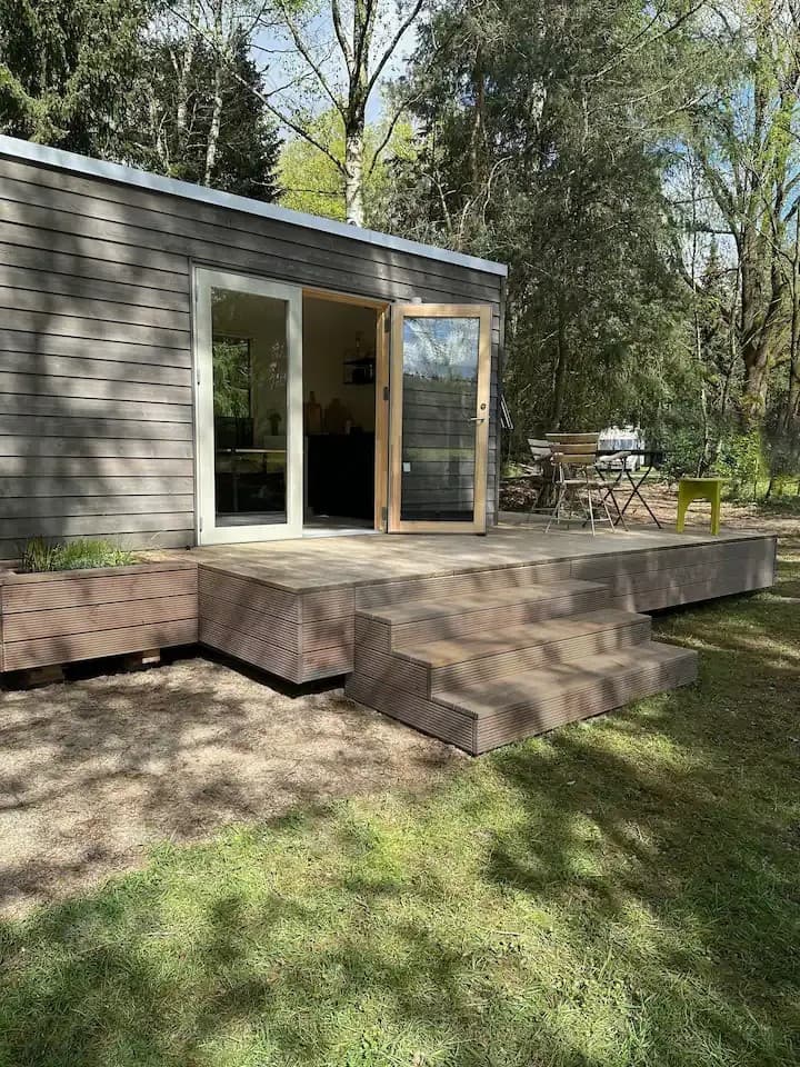 Außenansicht eines Tiny Houses in der Lüneburger Heide mit Bäumen ringsum