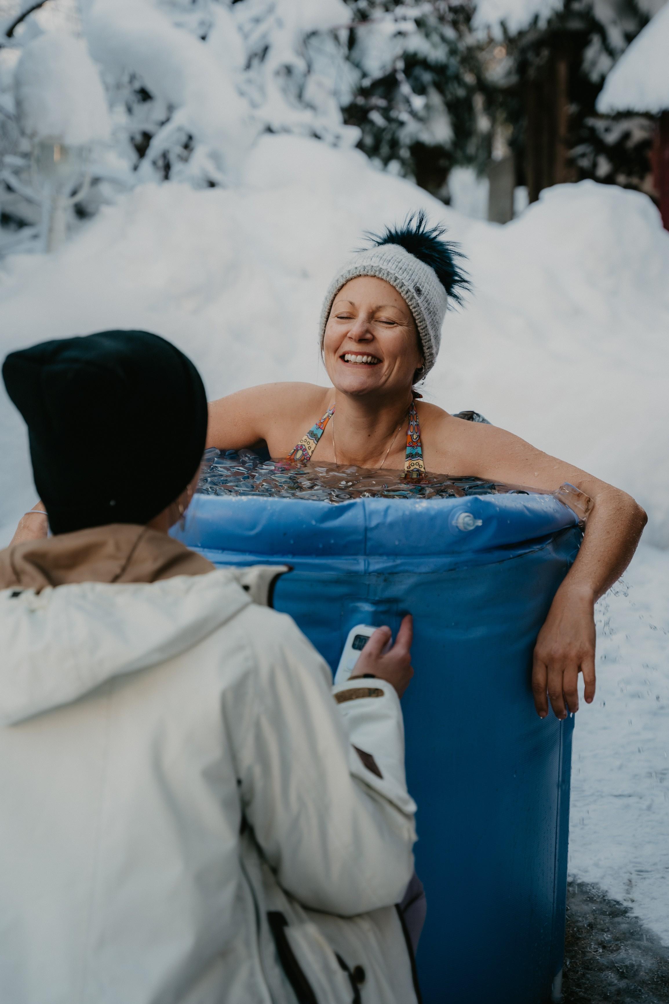 Eine lachende Frau in einer aufblasbaren Recovery Tub beim Eisbaden
