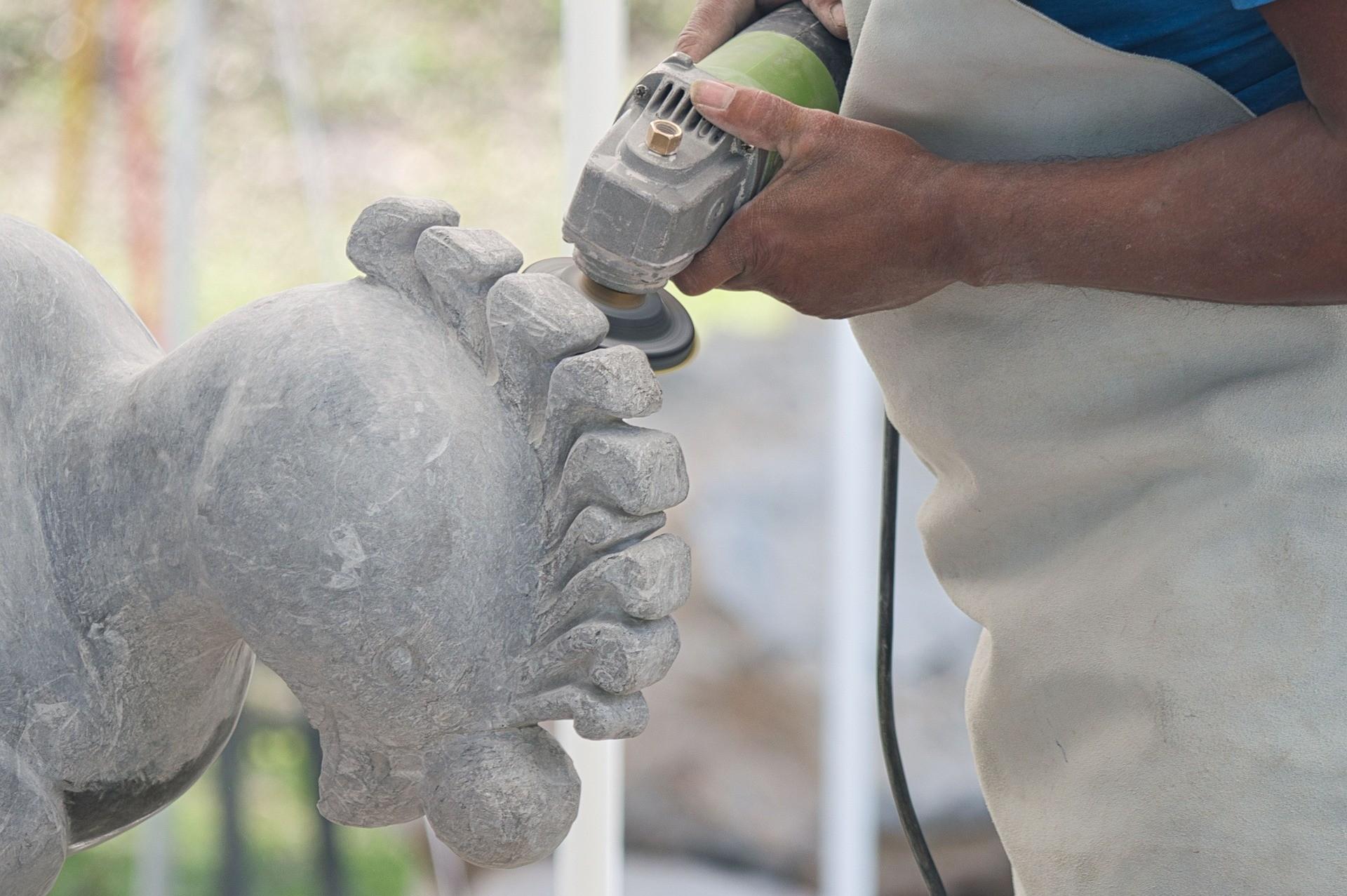 Eine Person arbeitet bei einem Steinbildhauer-Kurs mit einem Werkzeug an einem Stein