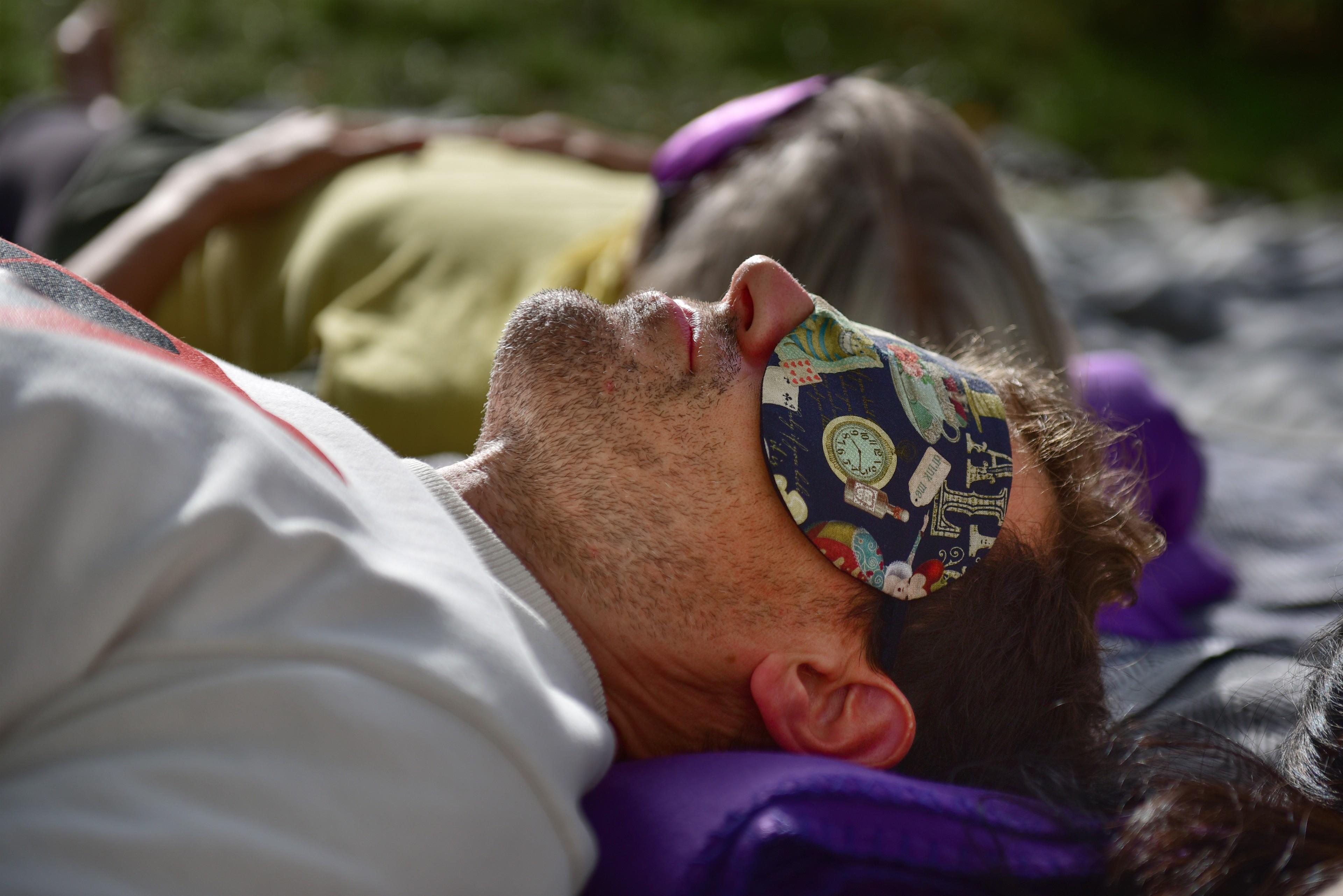 Ein Teilnehmer liegt bei einer Breathwork-Session mit einer Schlafmaske auf dem Rücken