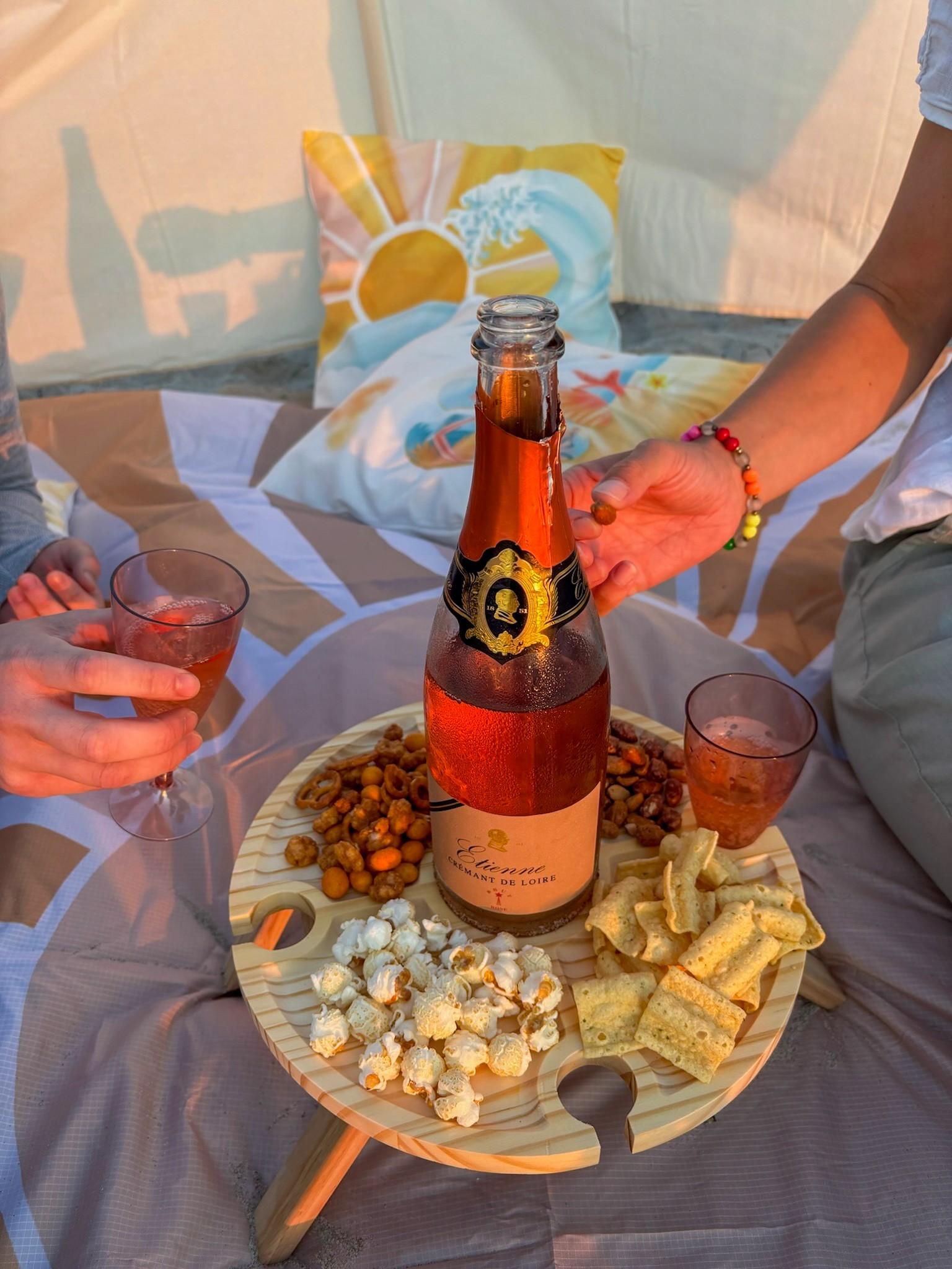 Ein Picknick am Strand von Warnemünde mit Snacks und einer Sektflasche auf einem kleinen Tisch