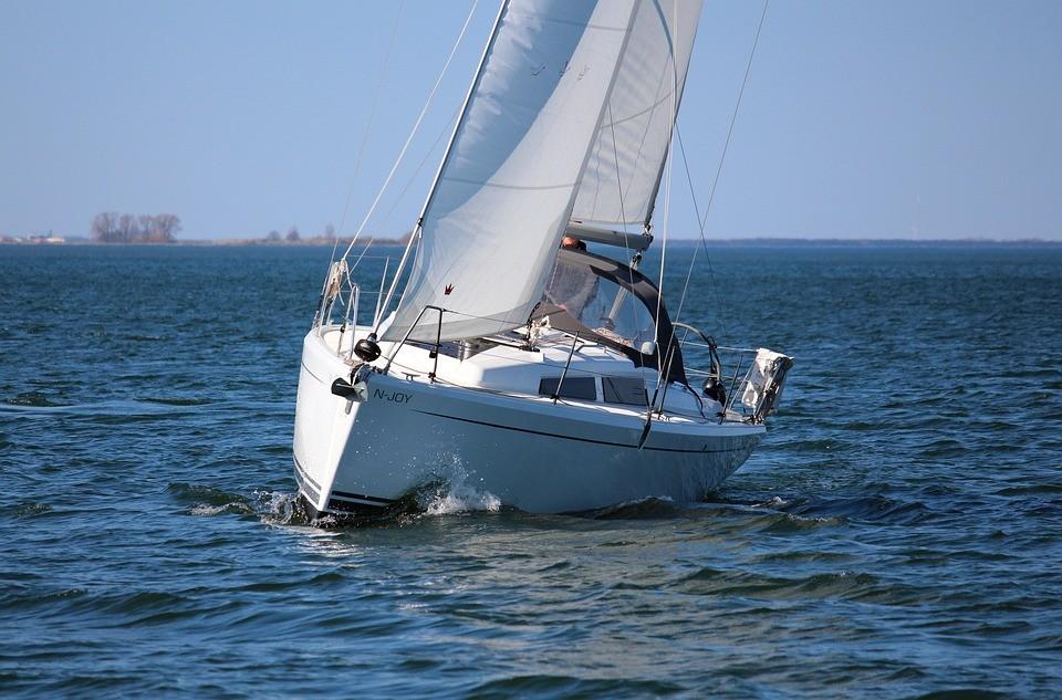 Ein kleines Segelboot mit geblähten Segeln an der Küste