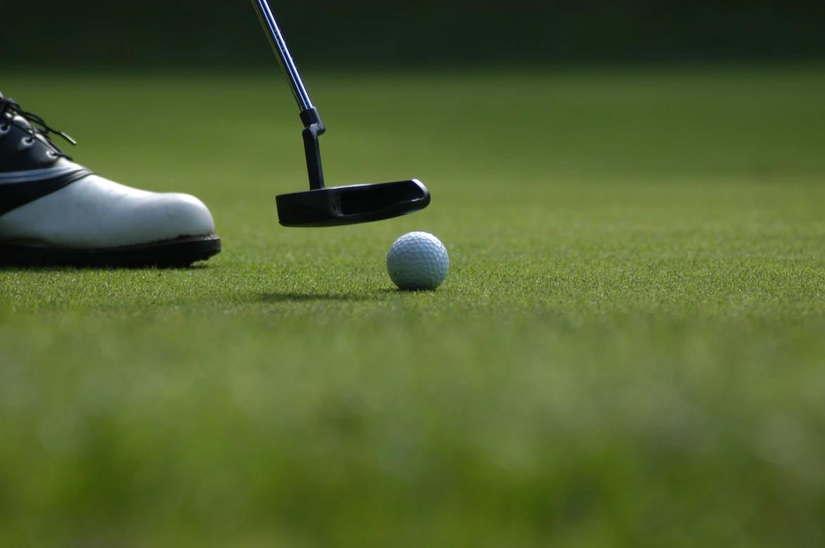 Eine Person mit Golfschläger und Ball auf dem Putting Green