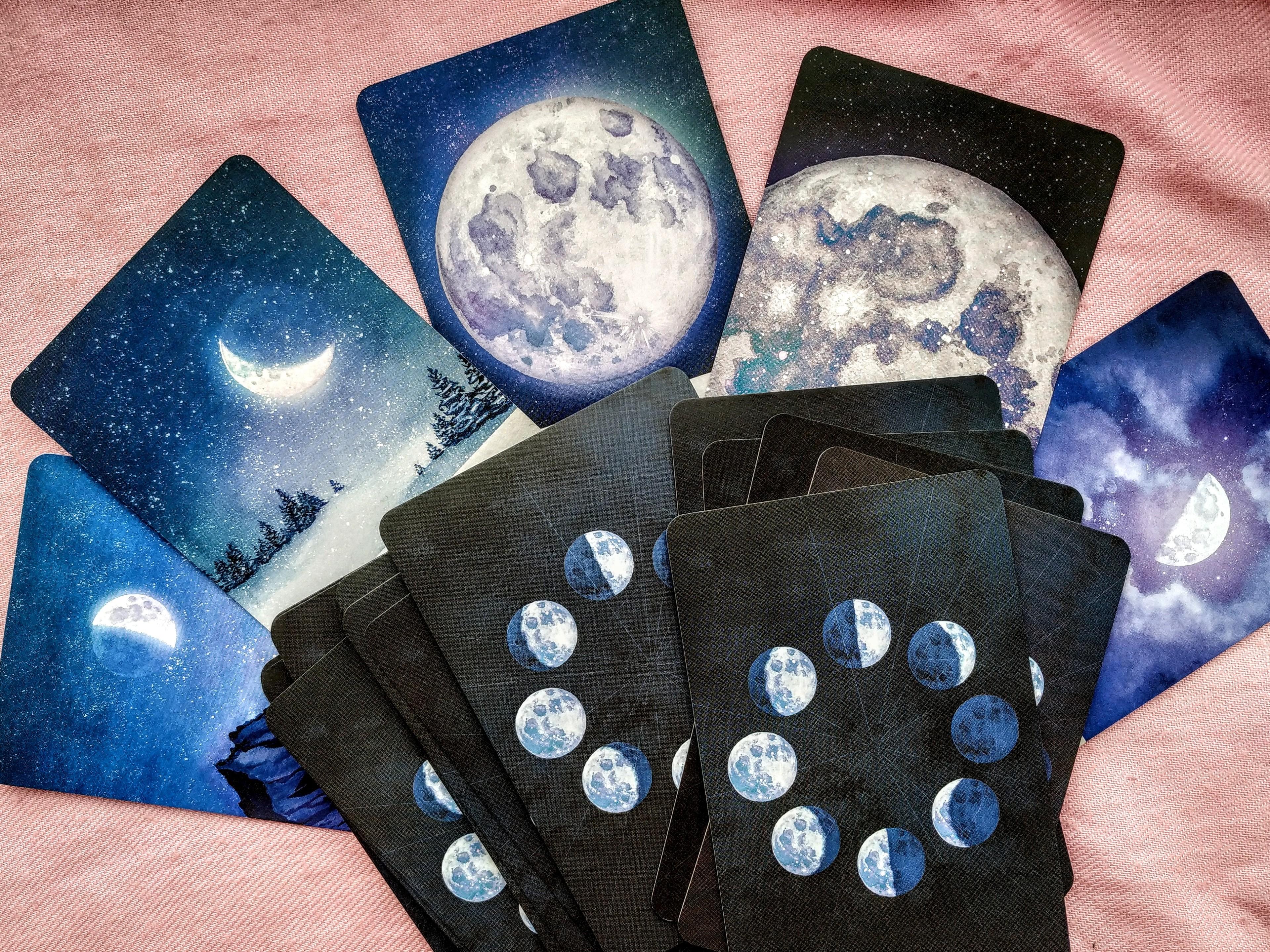 Spielkarten, die den Mond in verschiedenen Phasen abbilden, liegen auf einer Tischdecke