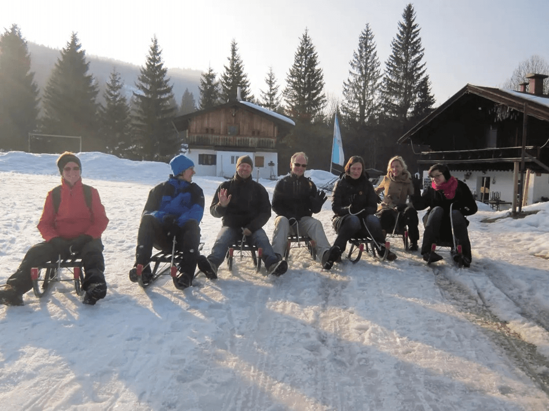 Eine Gruppe sitzt auf Schlitten beim Rodeln im Chiemgau