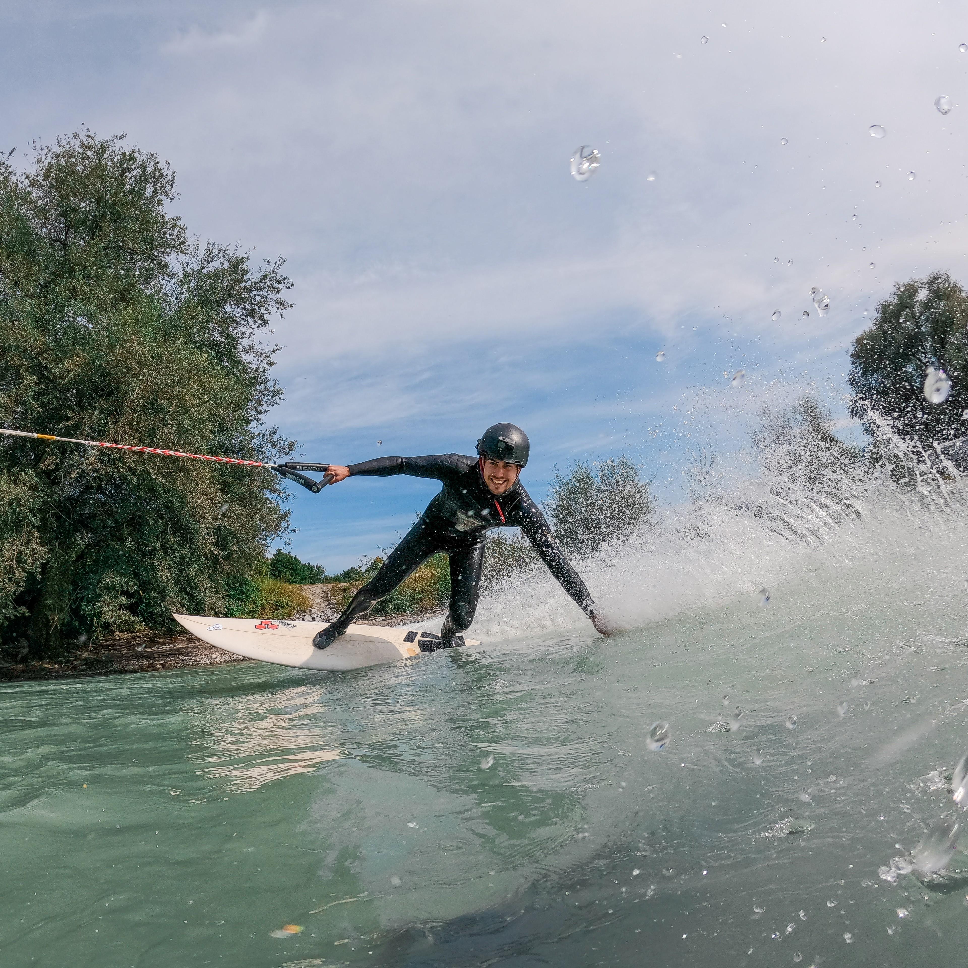 Eine Person lehnt sich beim Upstream-Surfing zur Seite und hält dabei ihre Hand ins Wasser