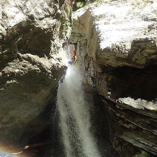 Eine Person seilt sich beim Canyoning in der Starzlachklamm durch einen Wasserfall ab