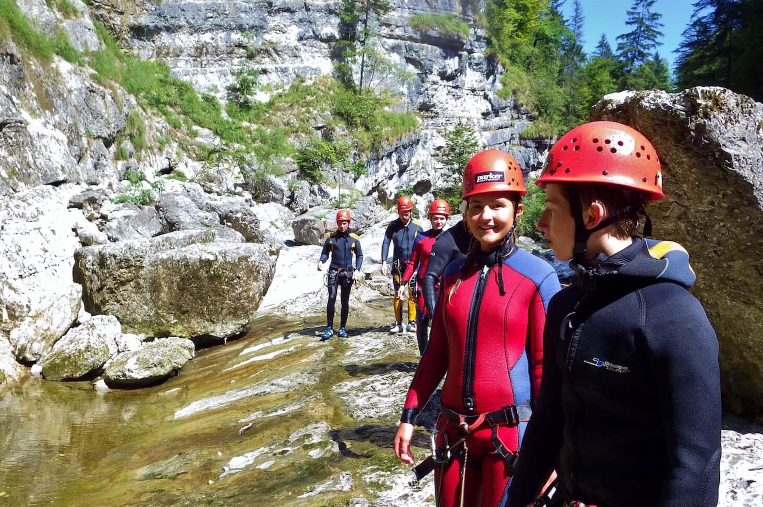 Eine Gruppe mit Neoprenanzügen und Helmen beim Canyoning