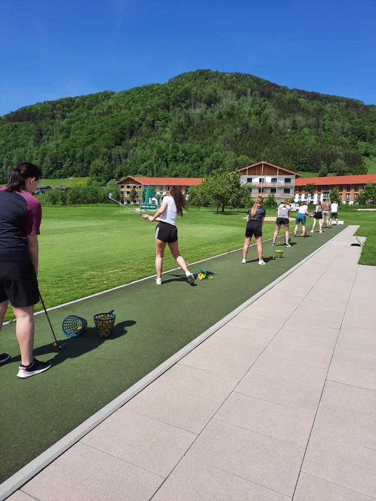 Golfer:innen stehen auf der Tee-Line und üben den Abschlag