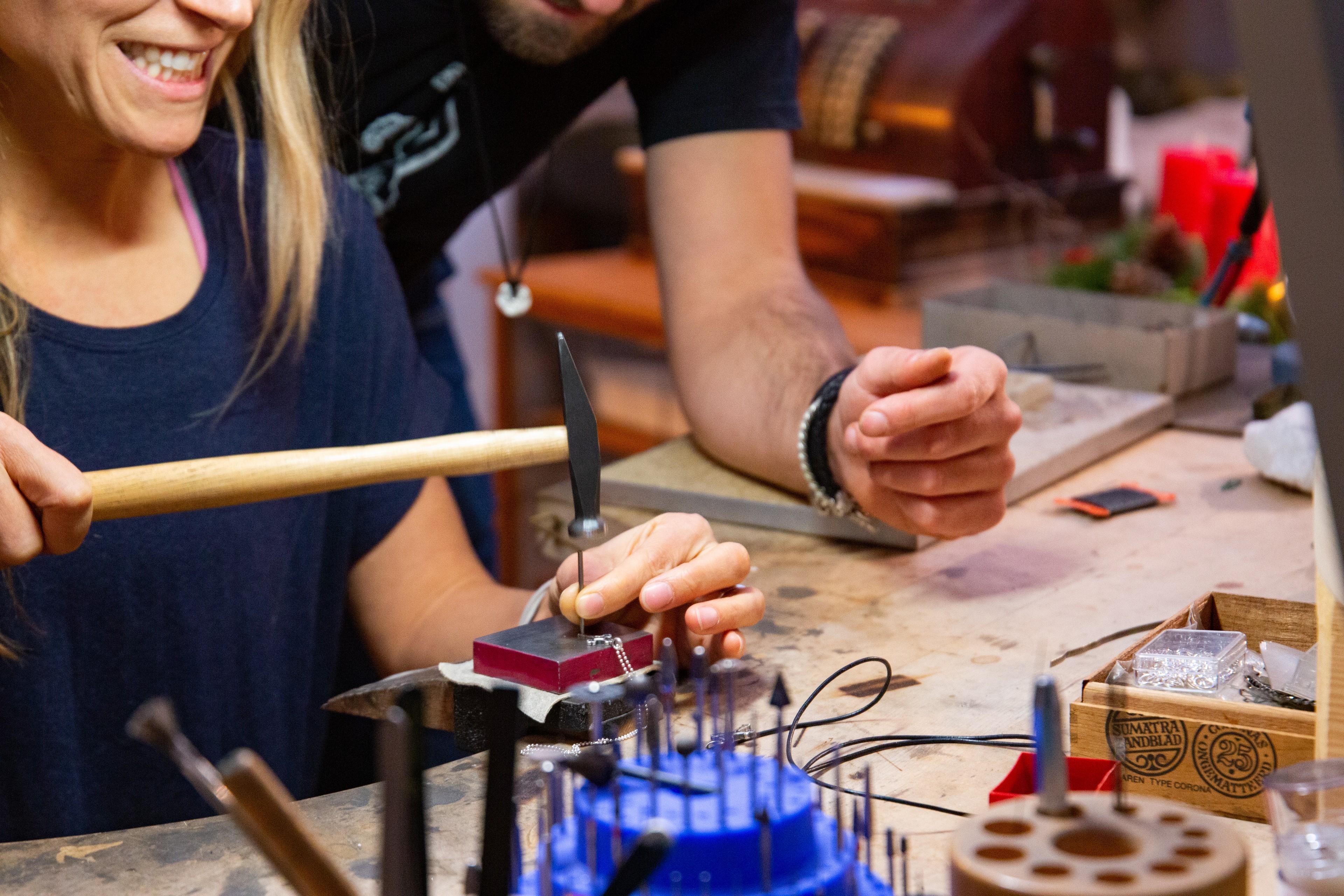 Teilnehmende stellen bei einem Schmuck-Workshop einen Gipfelkreuz-Anhänger her