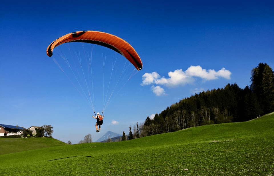Eine Person fliegt mit einem Gleitschirm wenige Meter über dem Boden