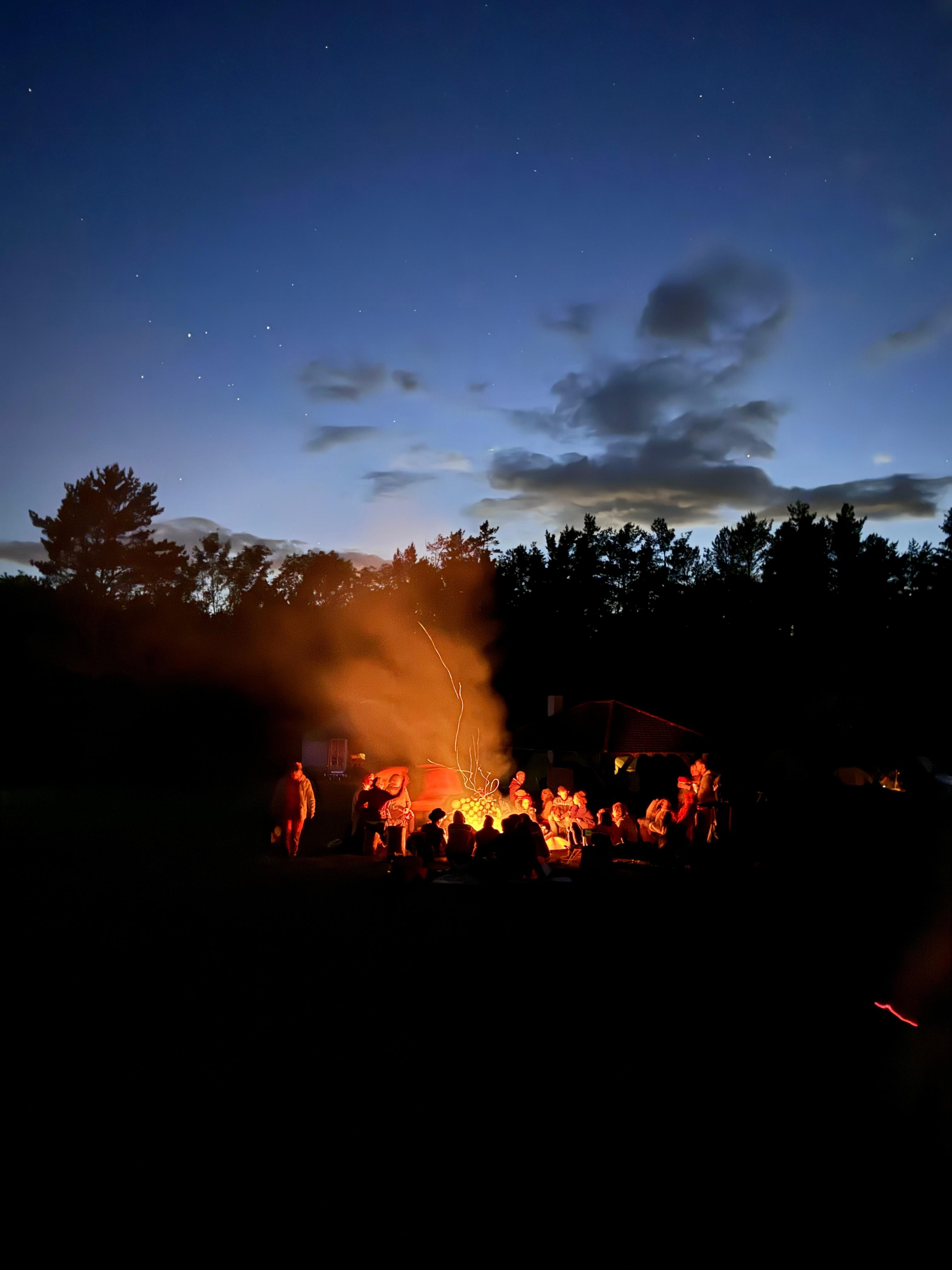 Eine Gruppe von Menschen sitzt während einer Kakao-Zeremonie um ein Lagerfeuer