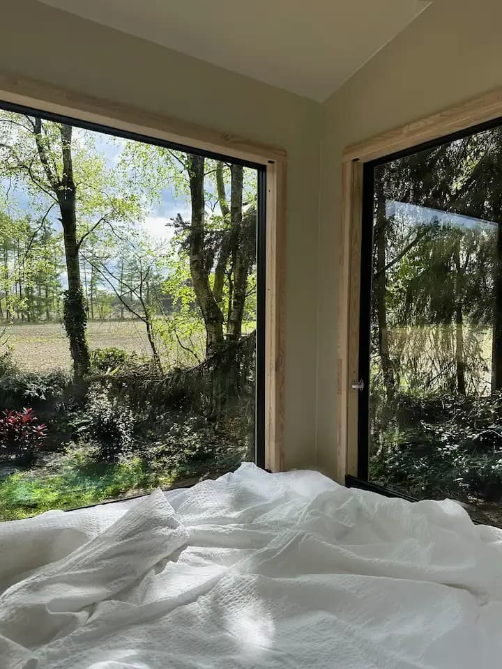 Blick durch die Fenster eines Tiny Houses in der Lüneburger Heide mit Aussicht ins Grüne