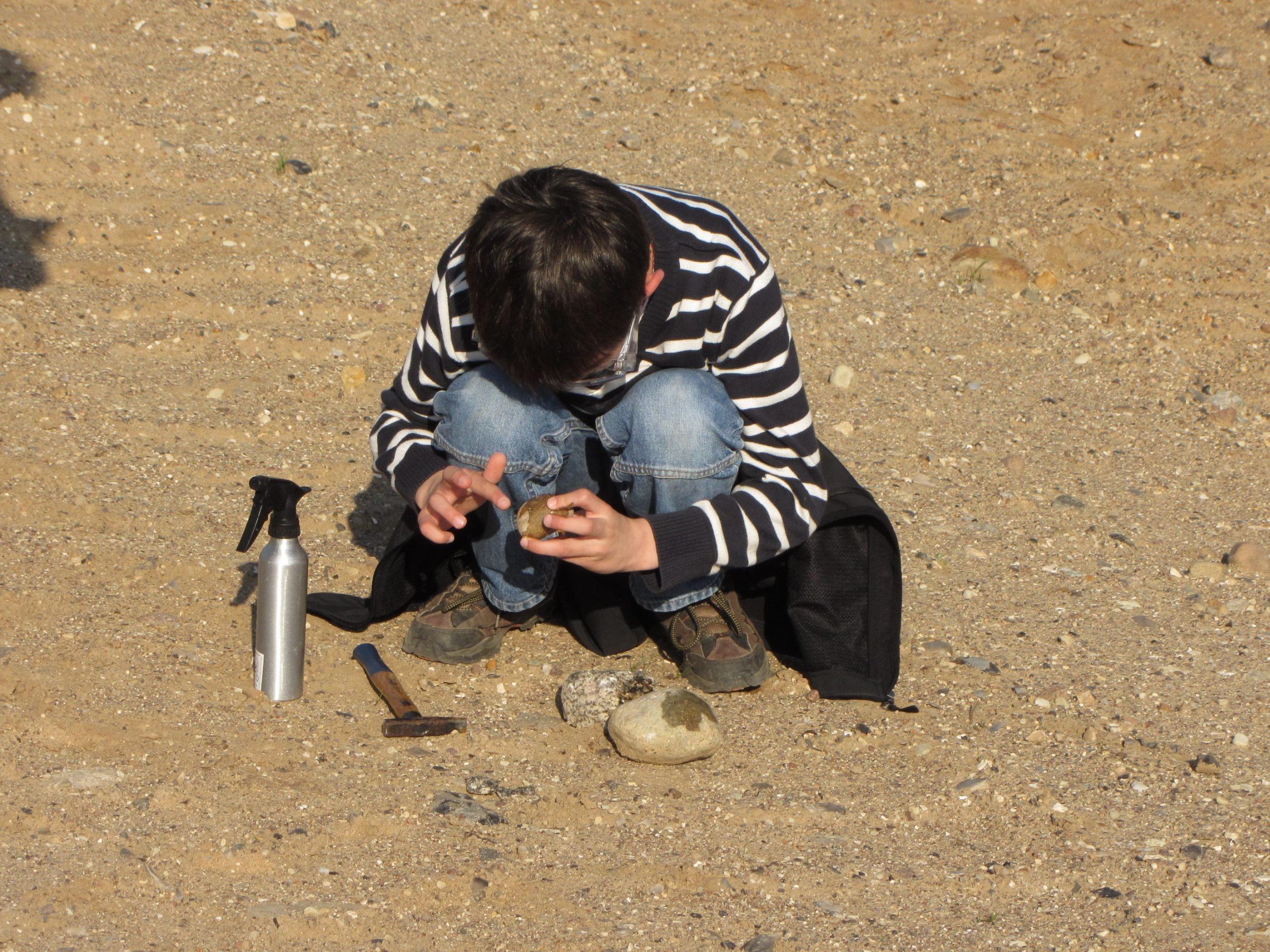 Ein Kind untersucht einen Stein bei einer Exkursion des Geoparks Nordisches Steinreich