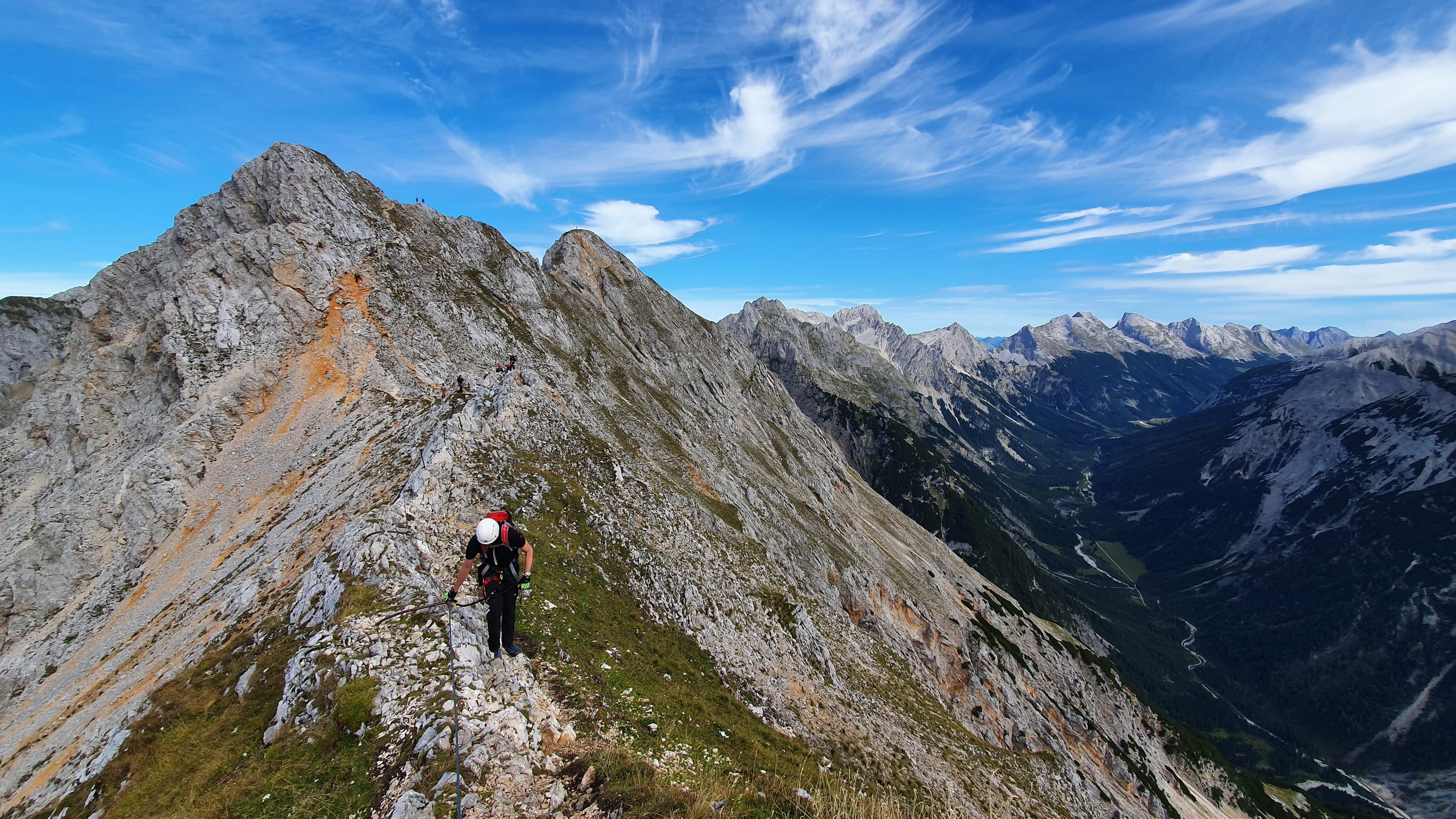 Eine Person auf dem Klettersteig Mittenwald mit Berggipfeln im Hintergrund