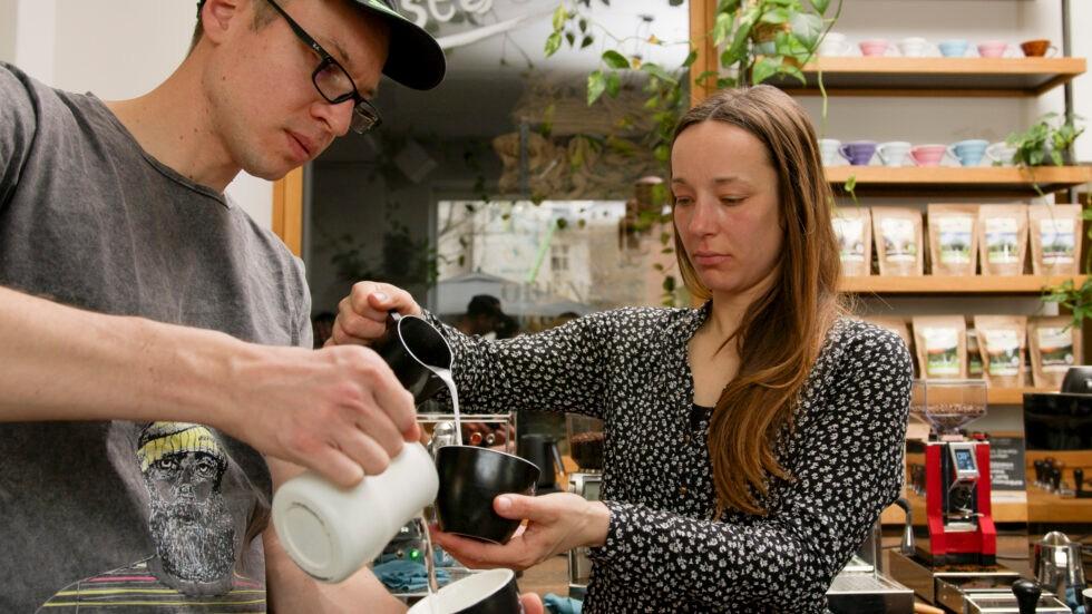 2 Personen gießen Milch beim Latte-Art-Kurs in Leipzig