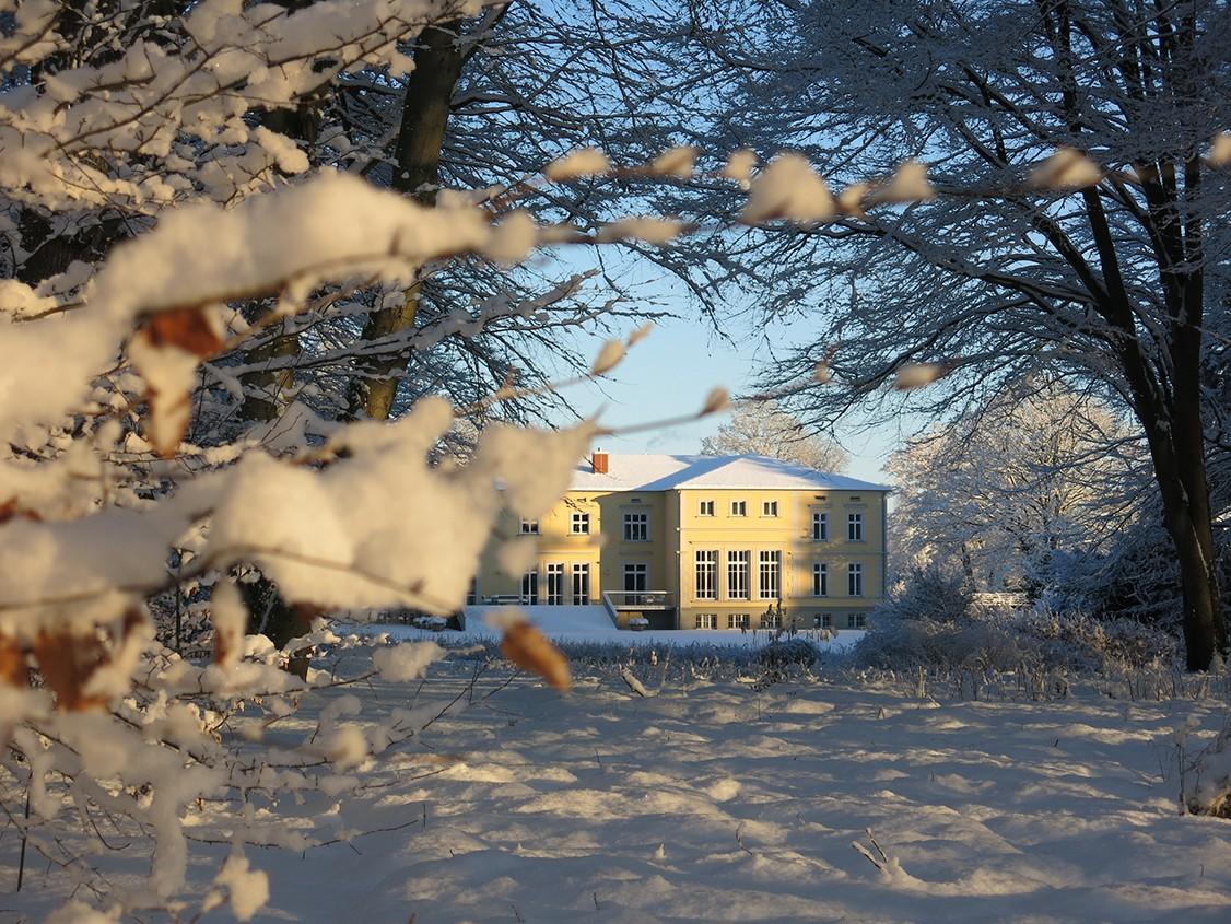 Gutshaus Landsdorf im Winter mit schneebedecktem Garten