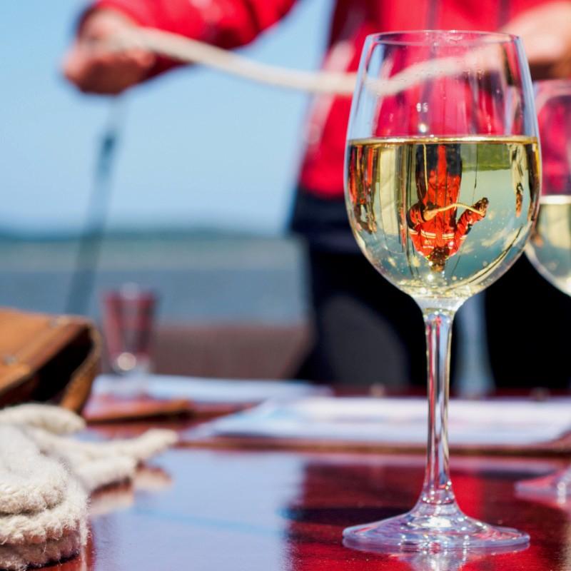 Ein Glas Wein steht auf einem Tisch auf dem Segelschiff „Weisse Düne“