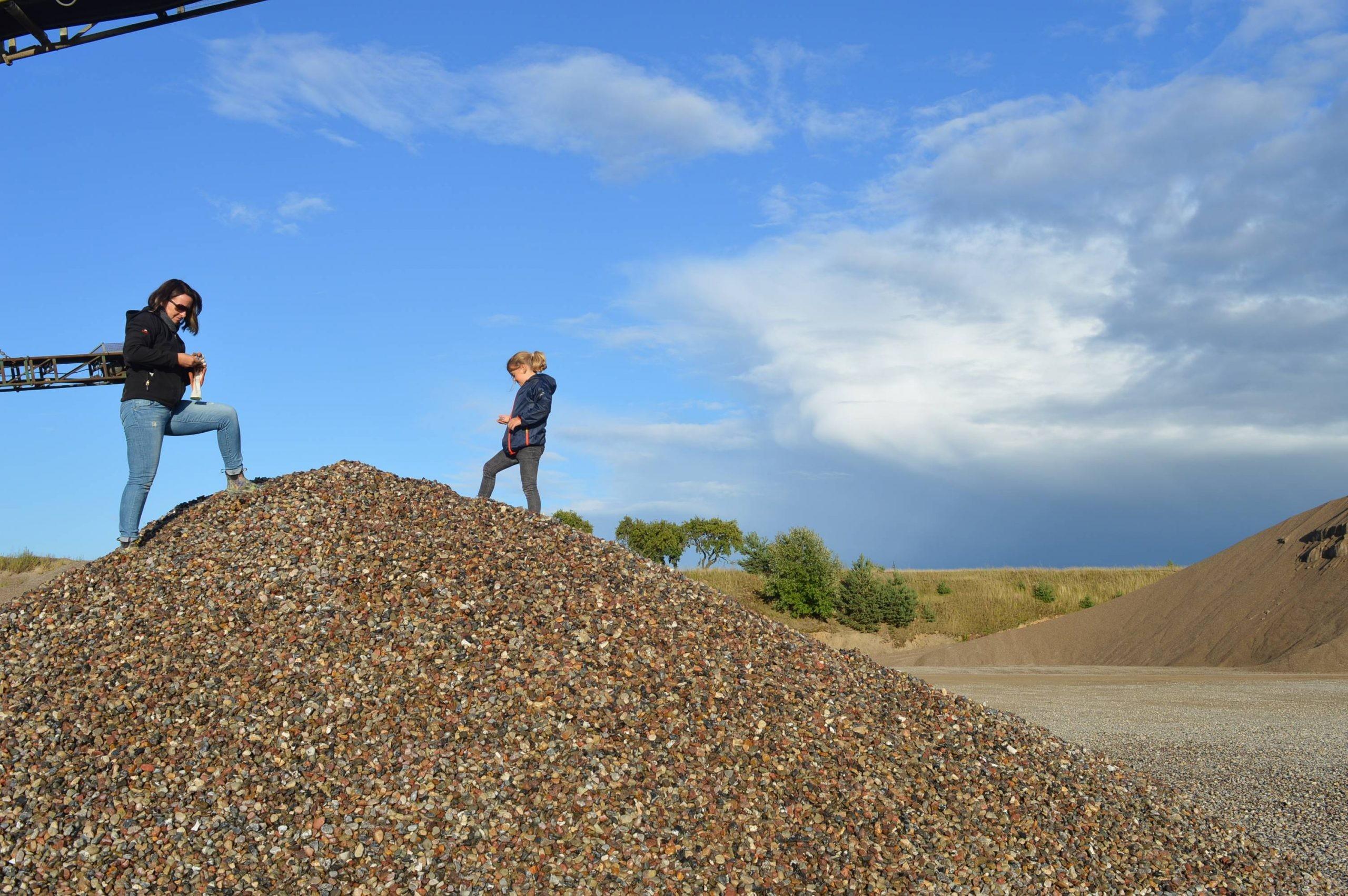 Eine Familie steht auf einem Steinhügel im Kieswerk Bark bei einer Exkursion des Geoparks Nordisches Steinreich