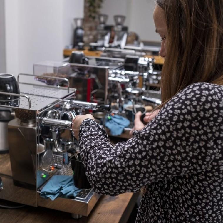 Personen bereiten bei einem Barista-Workshop Espresso an einer Siebträgermaschine zu