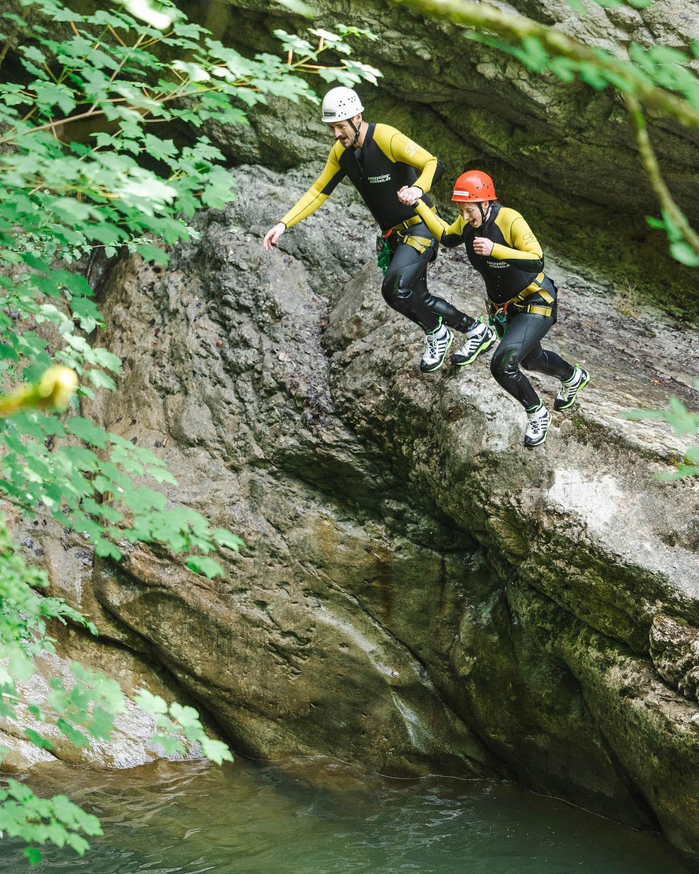 Zwei Personen springen beim Canyoning in der Starzlachklamm von einem Felsen